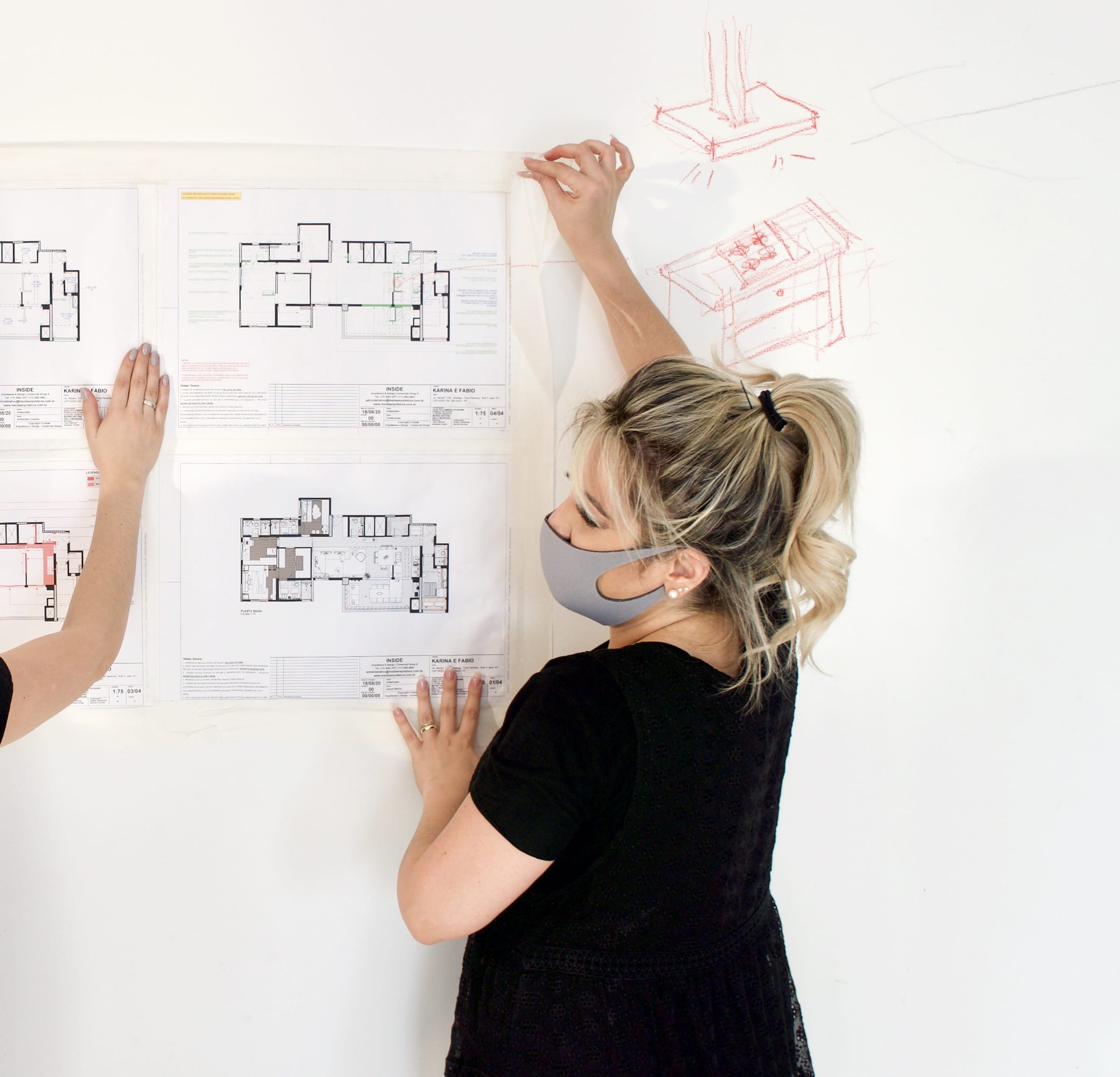 Sara Rollemberg segurando a planta do projeto na parede da obra, acervo INSIDE