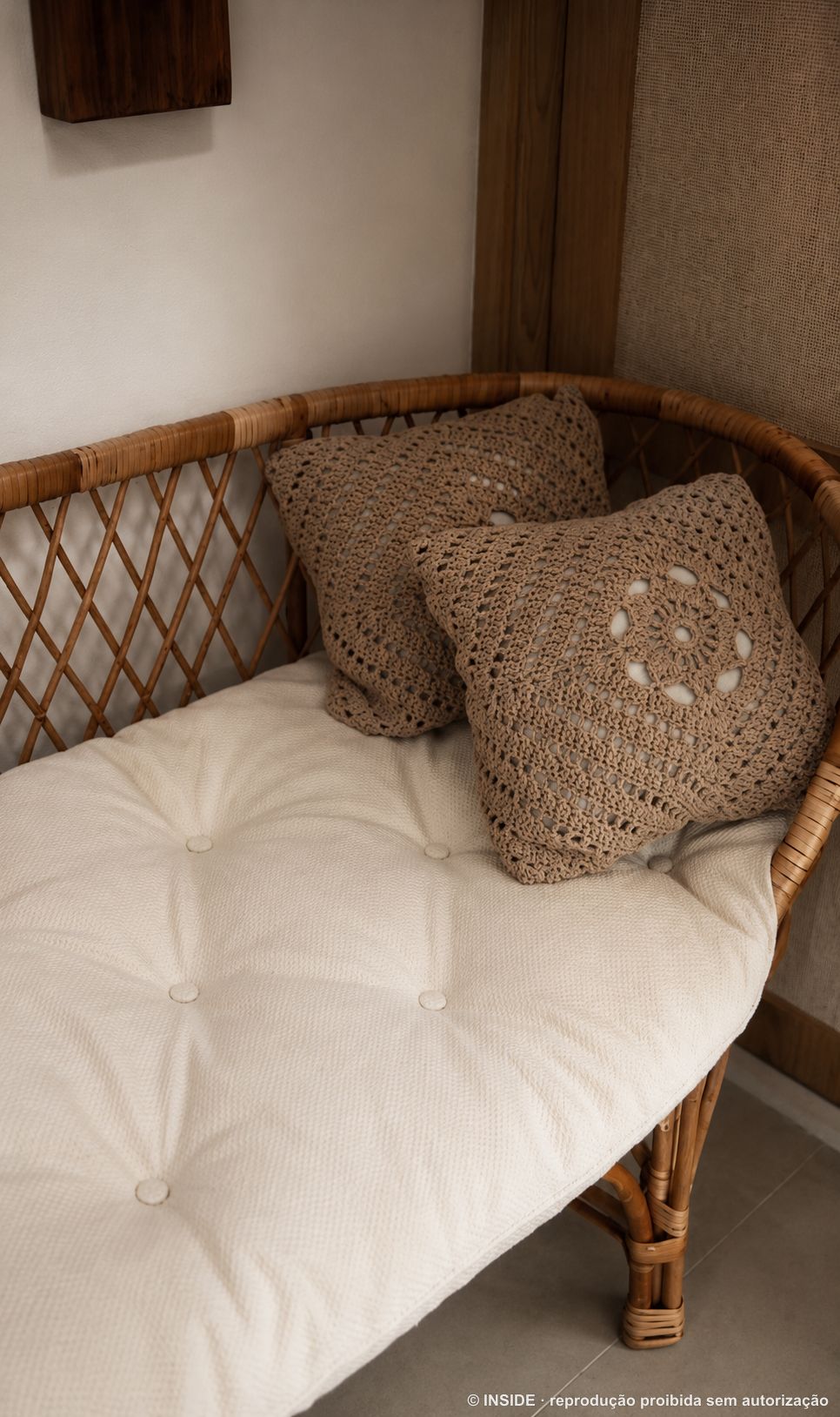 Almofadas de crochê artesanal sobre o banco de vime com futon claro, projeto INSIDE