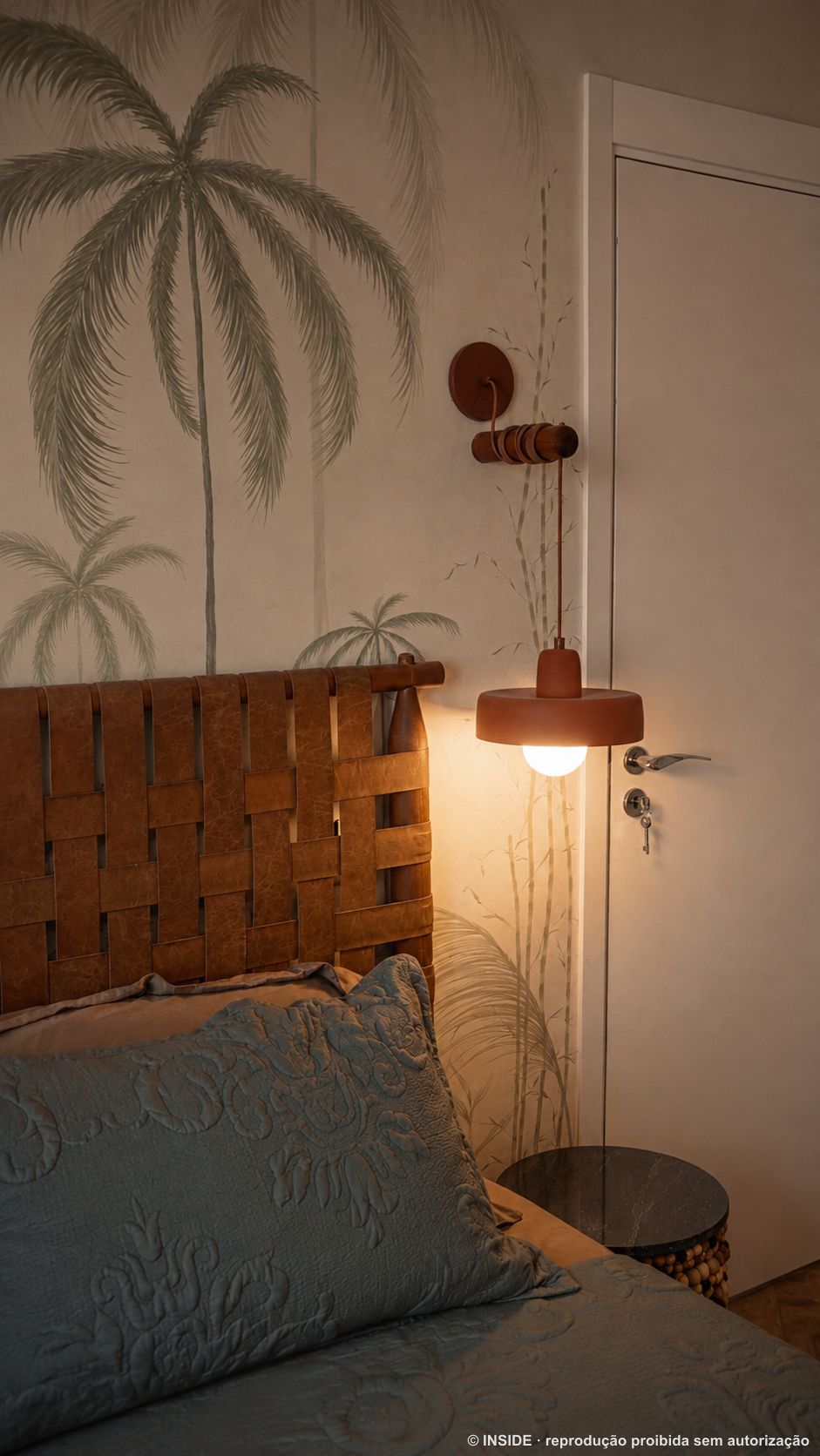 Luminária pendente de terracota presa a suporte artesanal de madeira na parede, ao lado da cama, com o mural de palmeiras ao fundo, projeto INSIDE