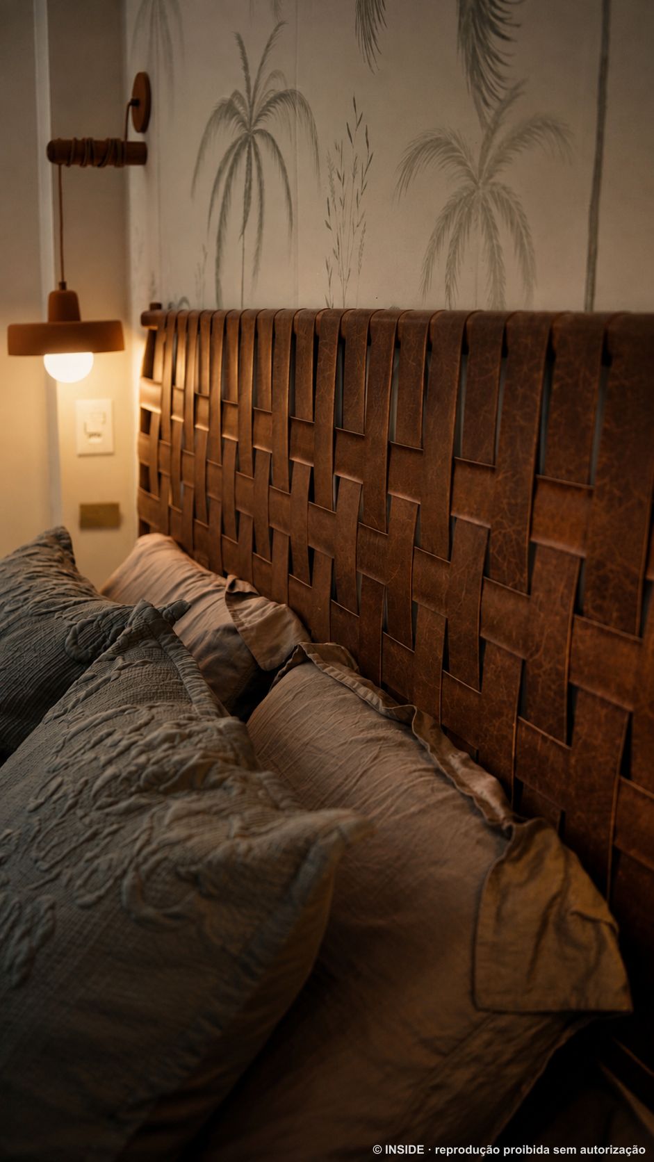 Cabeceira de couro trançado caramelo em close, com roupa de cama em azul e linho, projeto INSIDE
