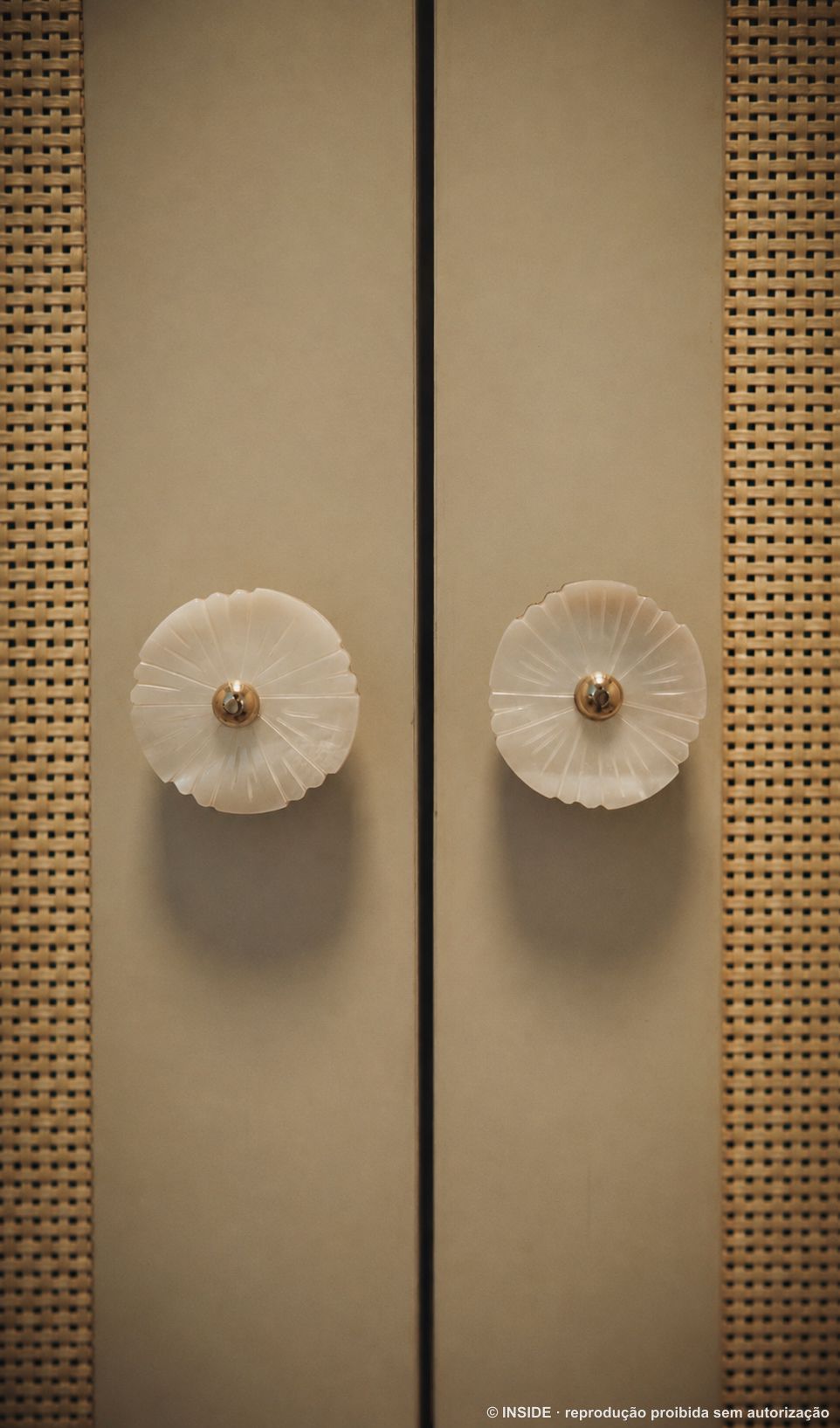 Par de puxadores de mármore em flor sobre portas de marcenaria com faixas de palha trançada, projeto INSIDE