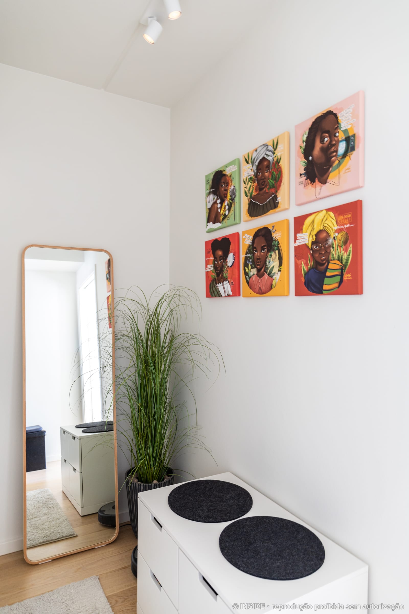 Corredor com quadros de retratos coloridos na parede e sapateira branca, projeto INSIDE em Copenhague, 2022