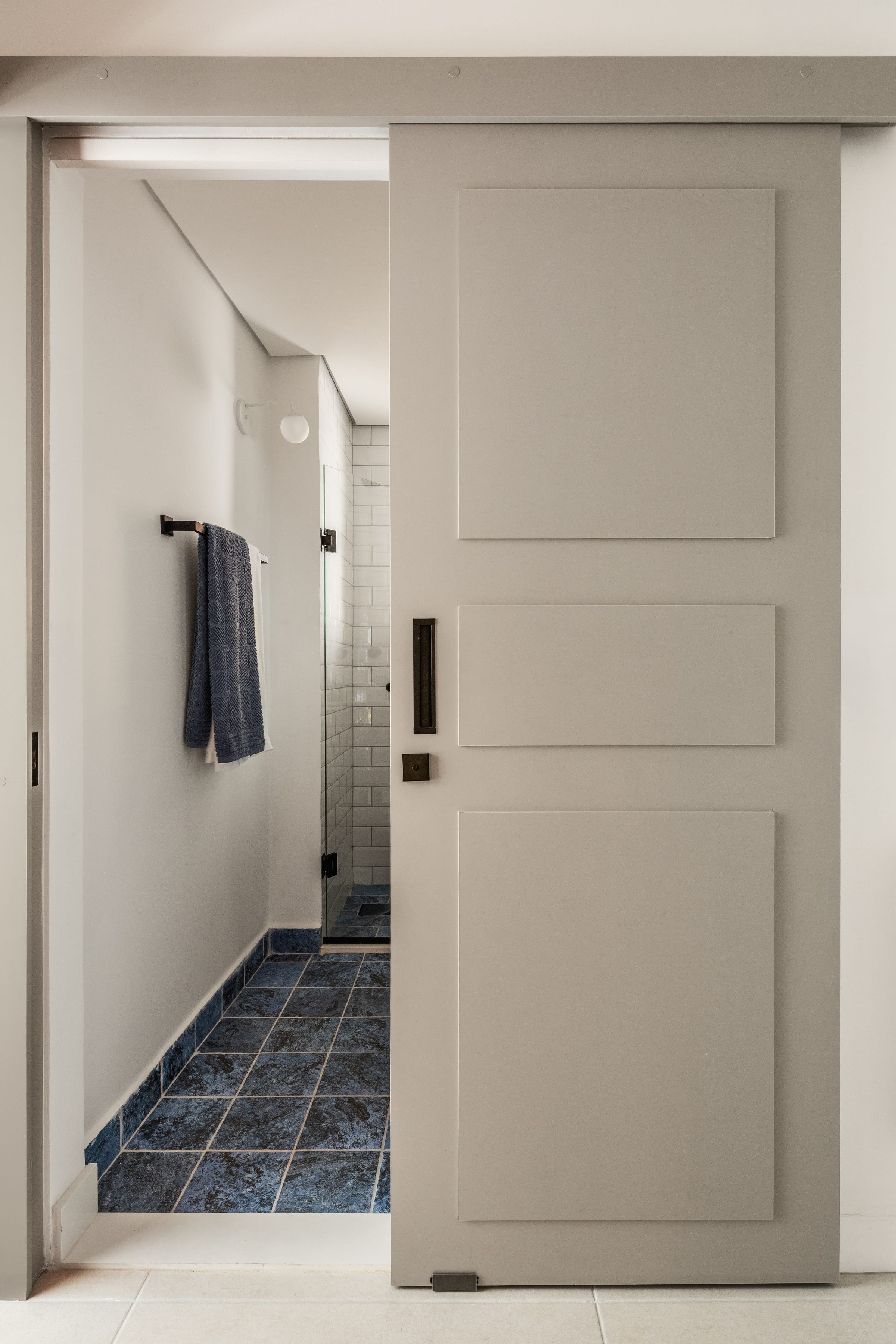 Banheiro social com piso azul, azulejo branco de metrô e porta de correr ripada, projeto INSIDE