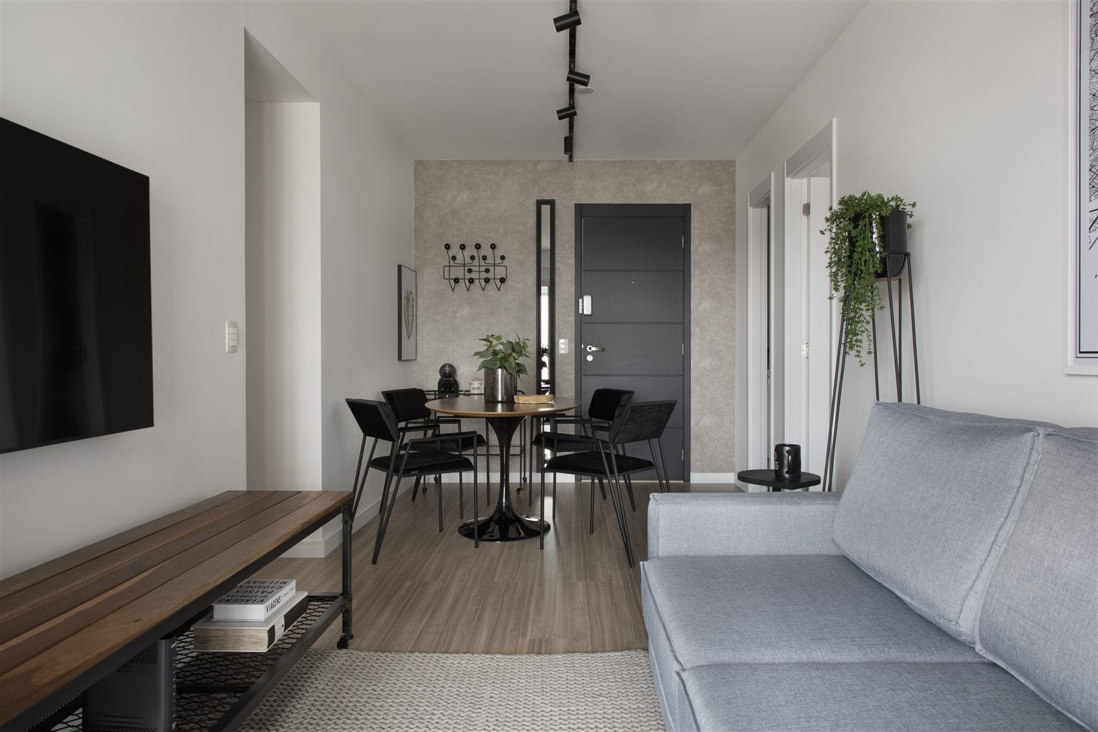 Sala de estar e jantar integradas com sofá cinza, mesa redonda de madeira e cadeiras pretas, apartamento alugado, projeto INSIDE