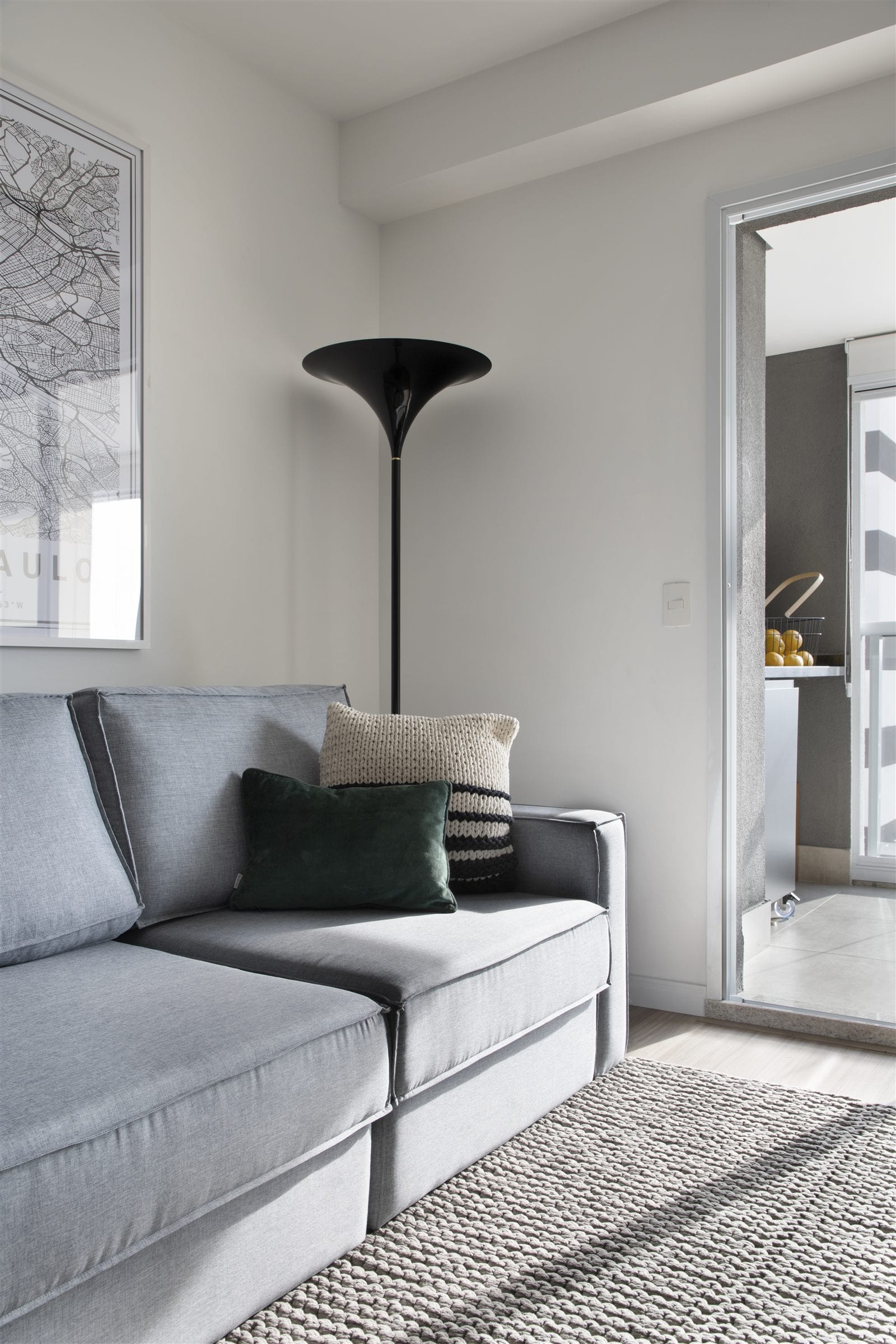 Sala de estar com sofá cinza, luminária de piso preta e passagem para a cozinha, apartamento alugado, projeto INSIDE