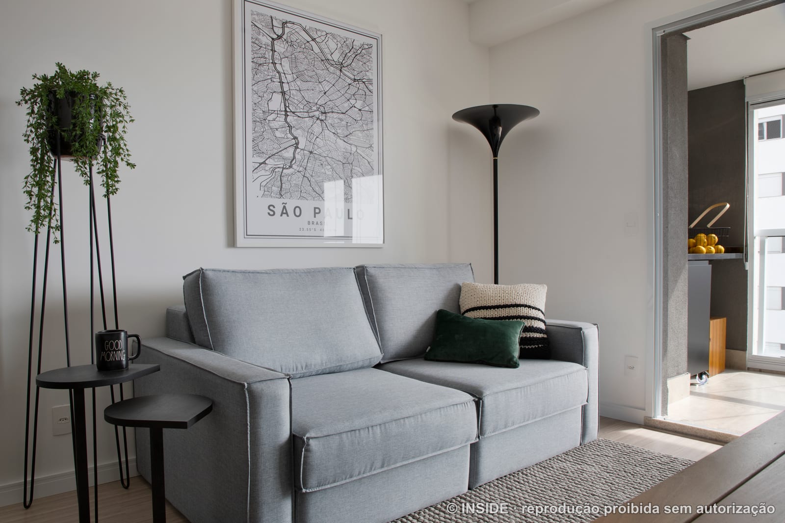Sala de estar com sofá cinza, luminária de piso e pôster do mapa de São Paulo, apartamento alugado, projeto INSIDE