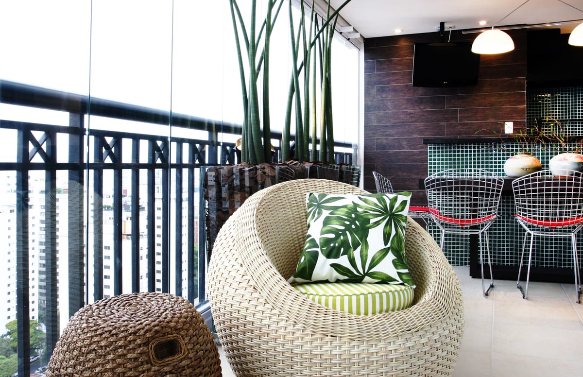 A varanda inteira: sansevierias em canteiro de vidro, poltrona de fibra e a cidade ao fundo. Paisagismo Villa Eco, projeto INSIDE, apartamento no Brooklin