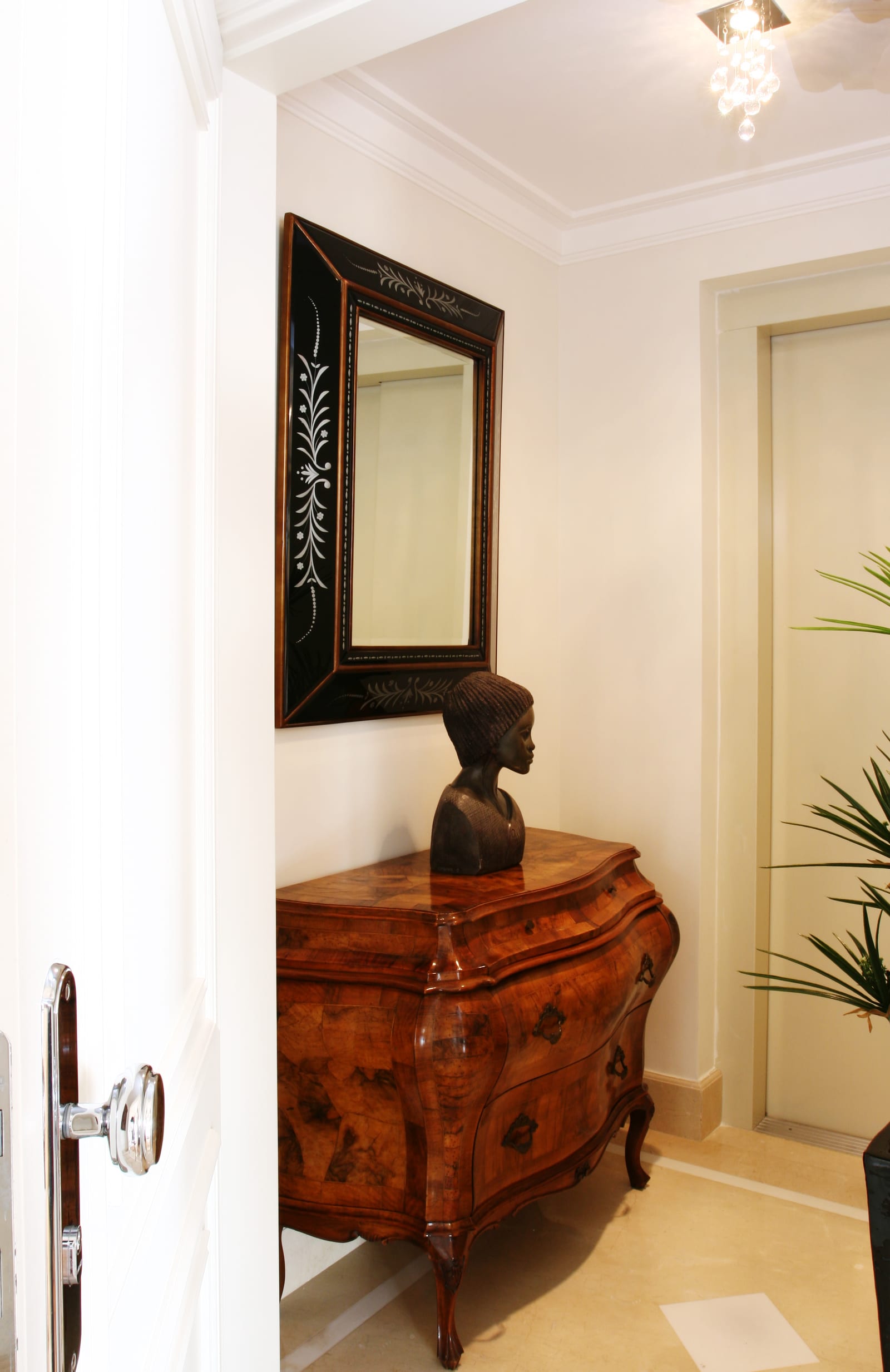 Hall de entrada com cômoda bombê de madeira, busto de bronze e espelho veneziano preto entalhado, projeto INSIDE