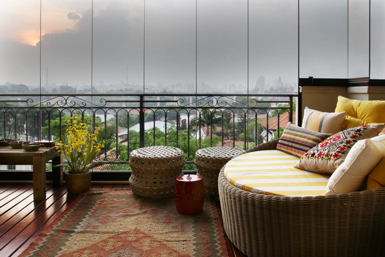 Varanda envidraçada com o skyline de São Paulo ao fundo, daybed listrado e kilim, projeto INSIDE