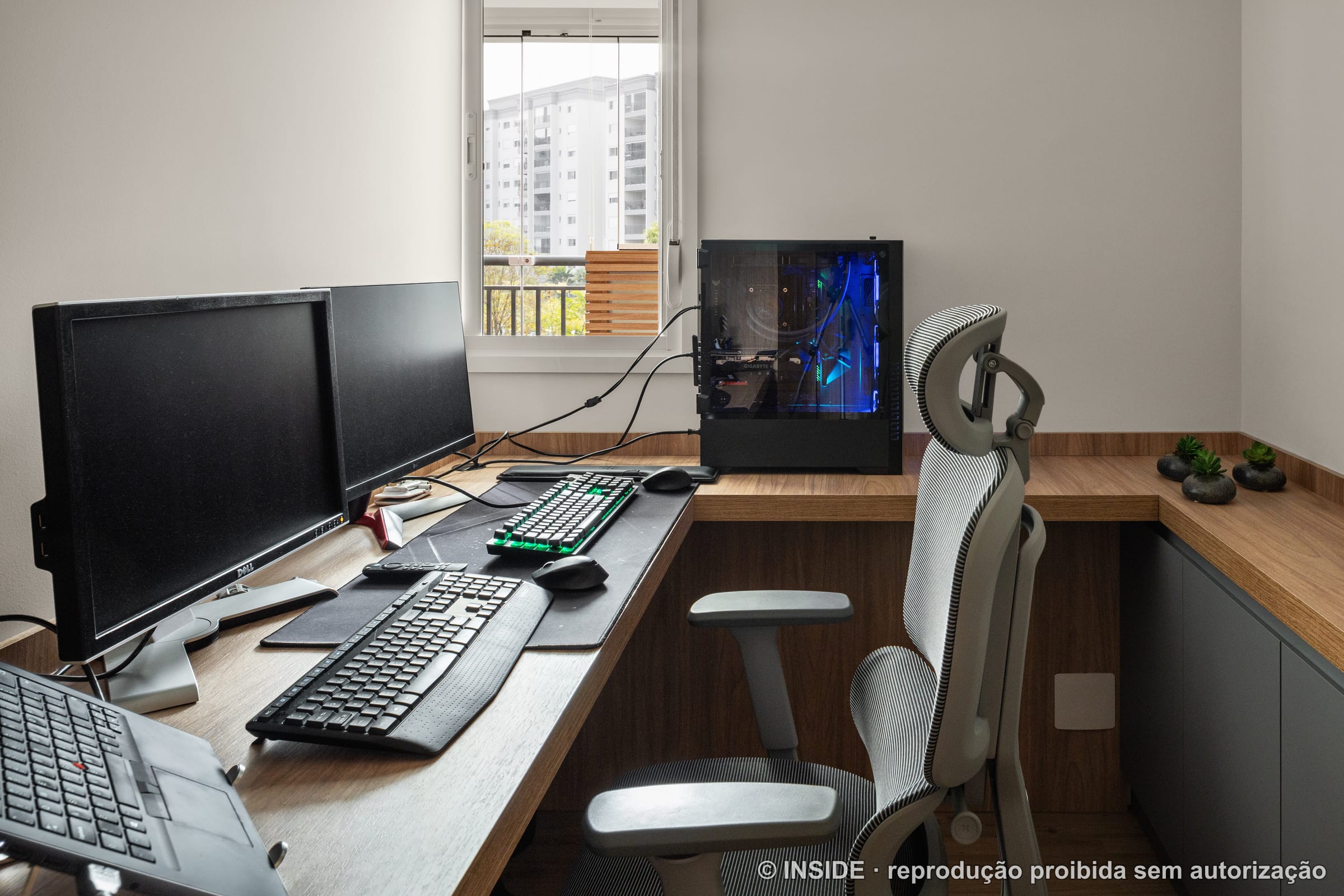 Home office com bancada em L, computador, cadeira e janela com vista da cidade, projeto INSIDE