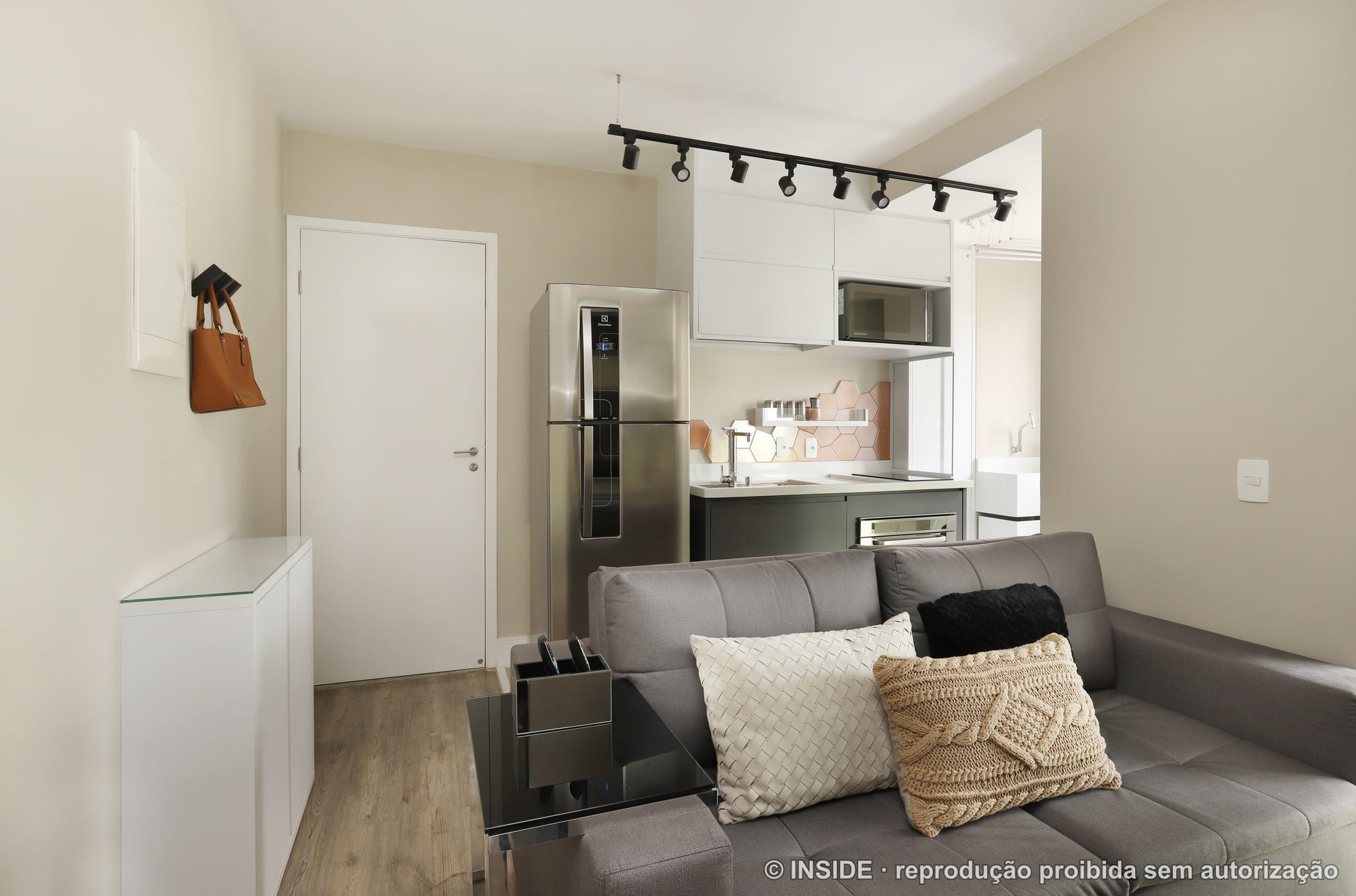 Sala de estar integrada em tons neutros, com sofá claro, tapete e almofadas, apartamento compacto na Lapa, projeto INSIDE