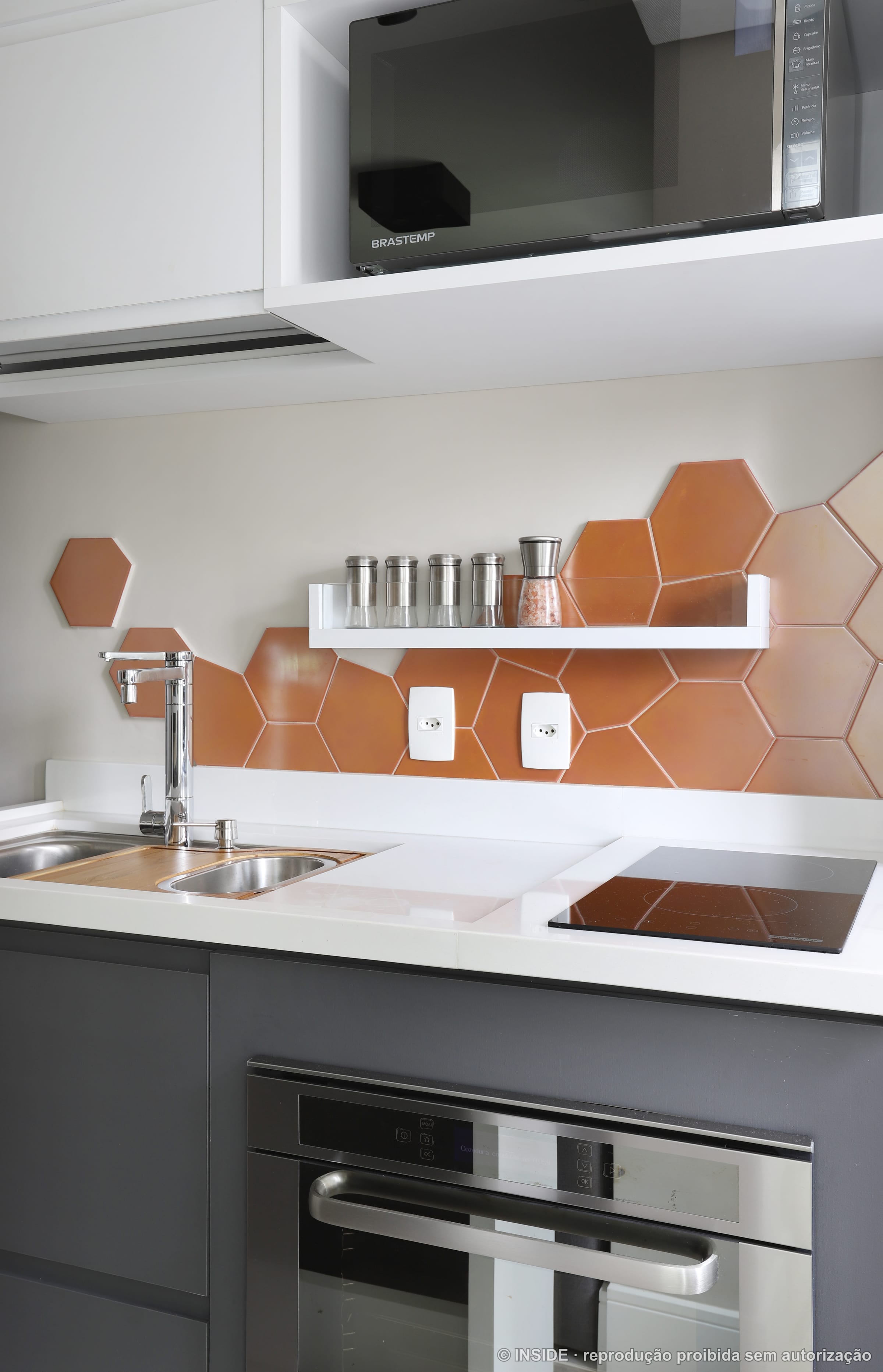 Cozinha compacta com backsplash de pastilhas hexagonais em cobre, bancada branca e prateleira, projeto INSIDE