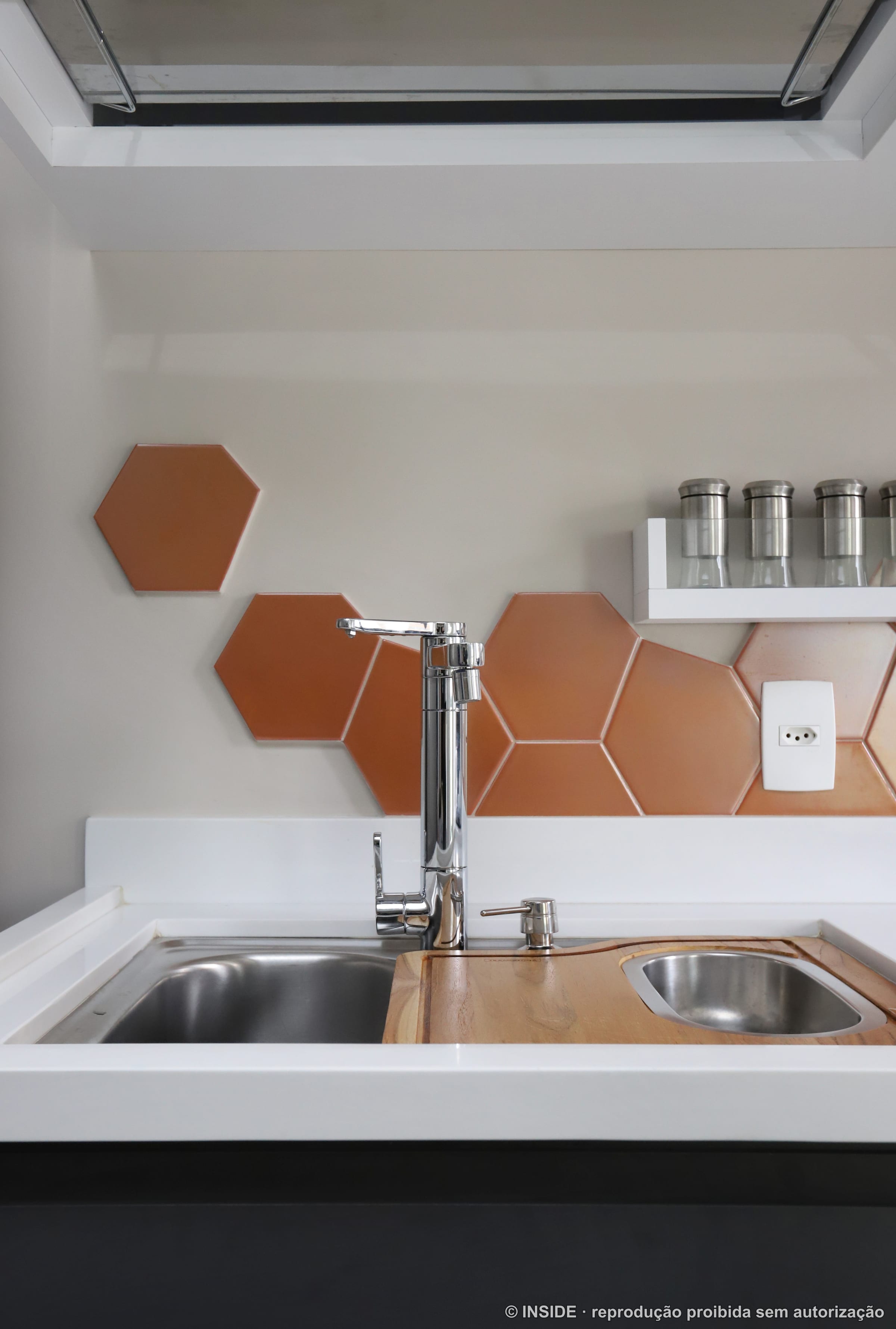 Detalhe da parede de pastilhas hexagonais de cobre com prateleira e temperos, projeto INSIDE