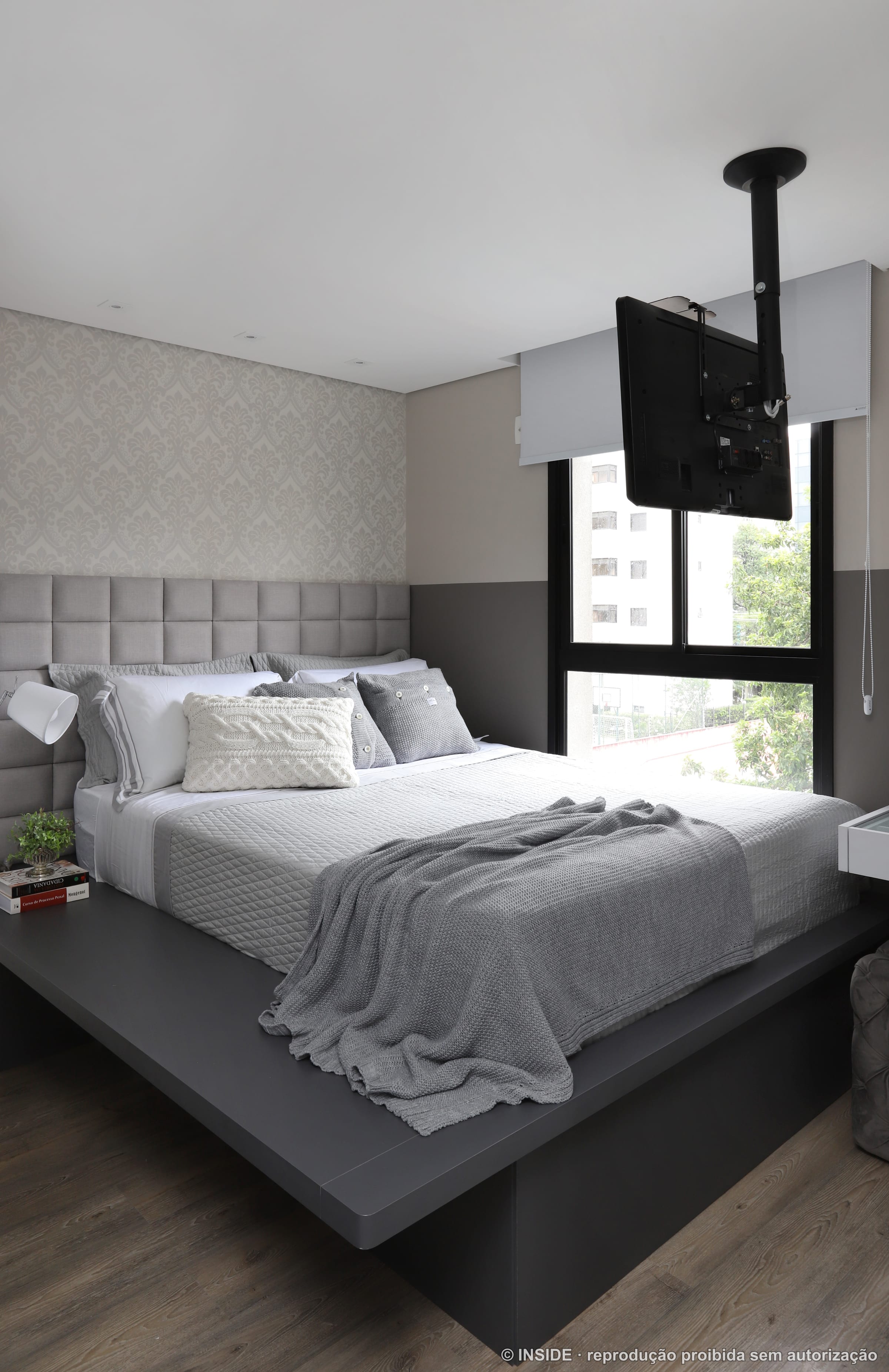 Quarto de casal com cabeceira estofada em painel cinza, roupa de cama neutra e televisão, projeto INSIDE