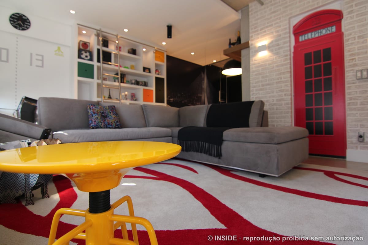 Sala de estar com cabine telefônica vermelha de Londres, mesa Ghost amarela e tapete gráfico, tema urbano, projeto INSIDE