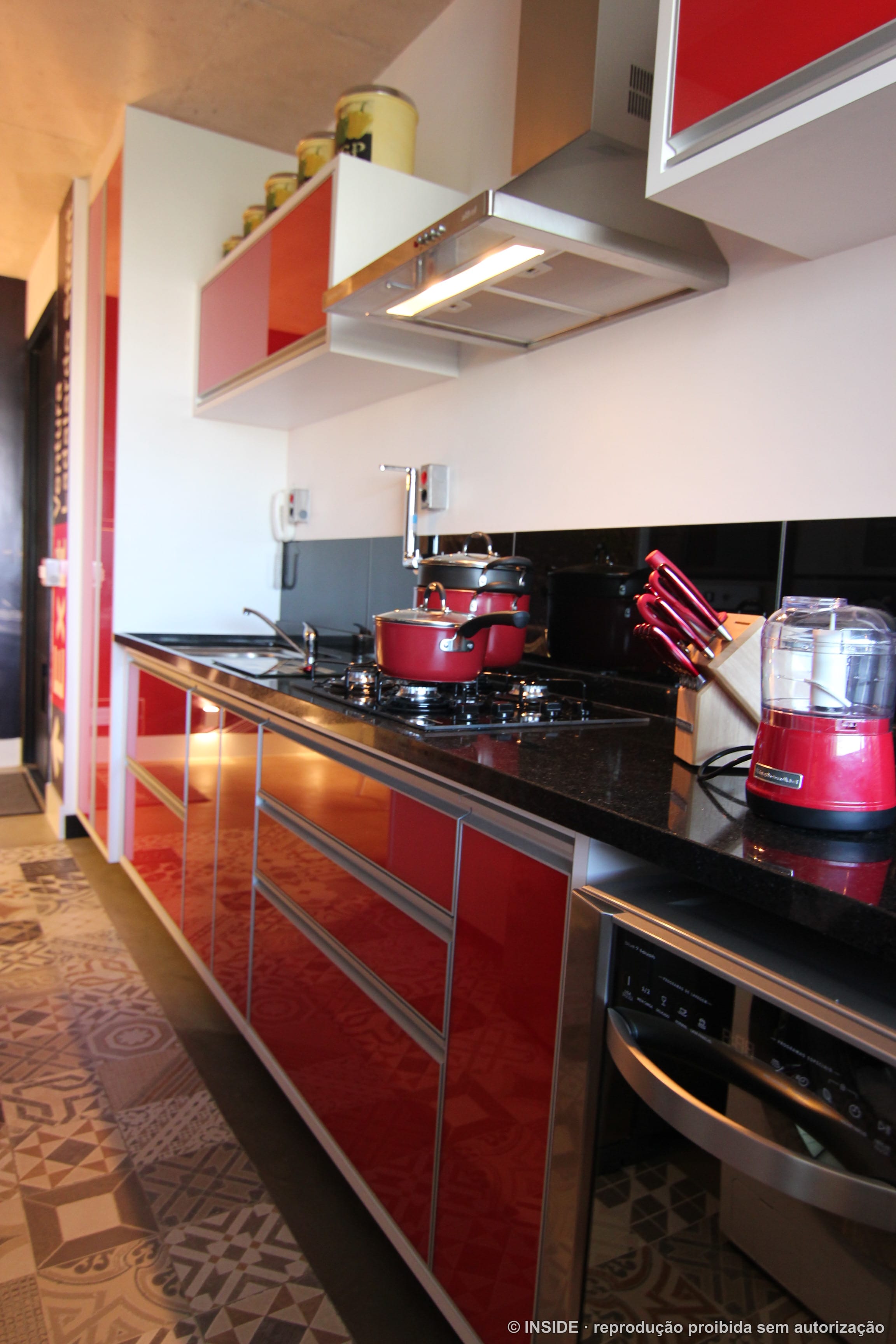 Cozinha com marcenaria em laca vermelha e preta, bancada escura e iluminação embutida, projeto INSIDE