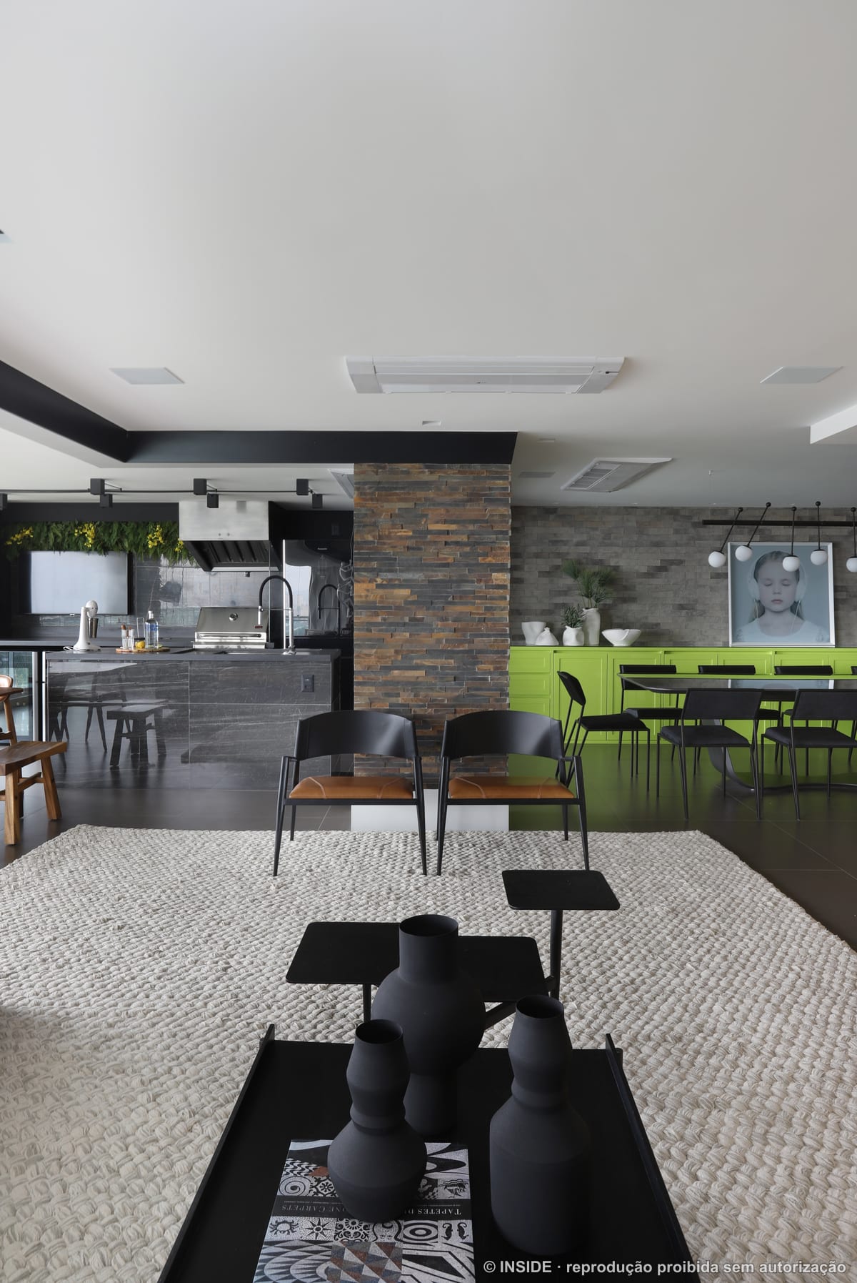 Sala de estar ampla com sofá modular, parede de pedra empilhada e piso-teto envidraçado com vista da cidade, projeto INSIDE