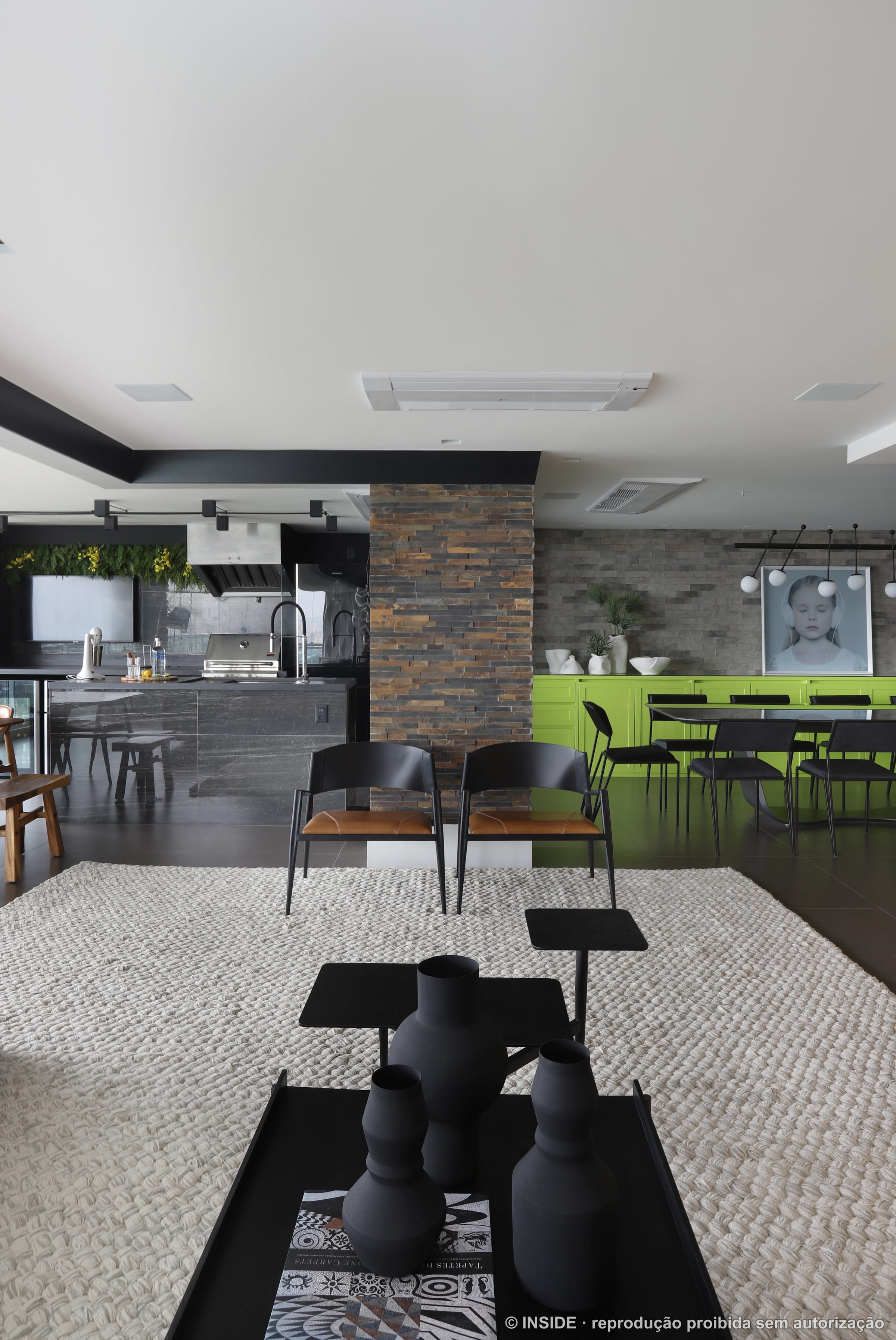 Sala de estar ampla com sofá modular, parede de pedra empilhada e piso-teto envidraçado com vista da cidade, projeto INSIDE