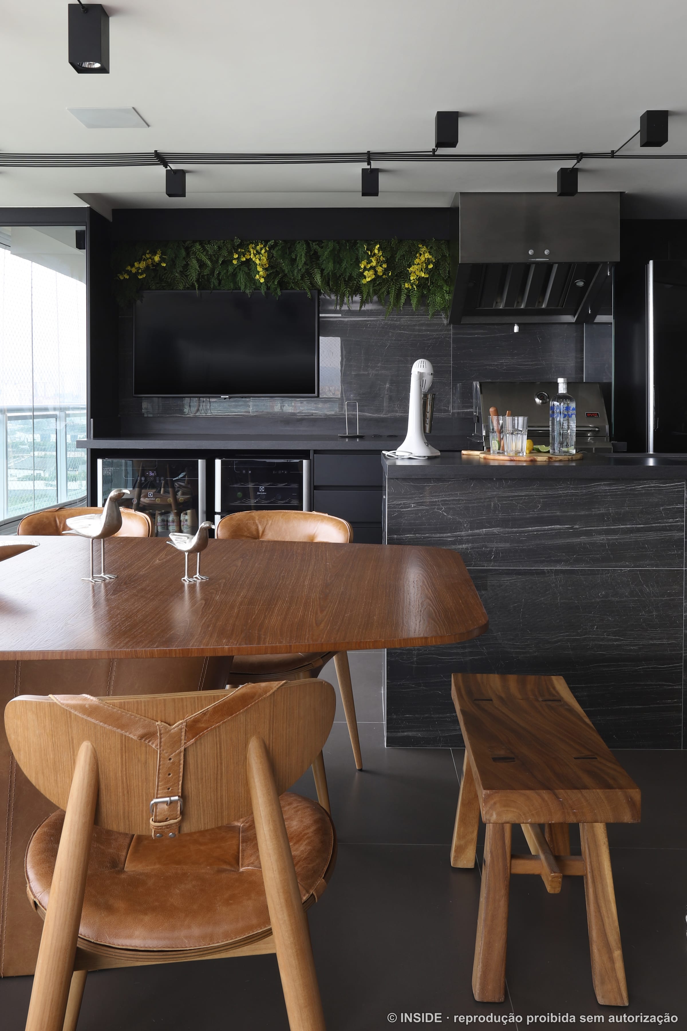 Varanda gourmet com mesa de madeira, churrasqueira e televisão, integrada ao estar, projeto INSIDE