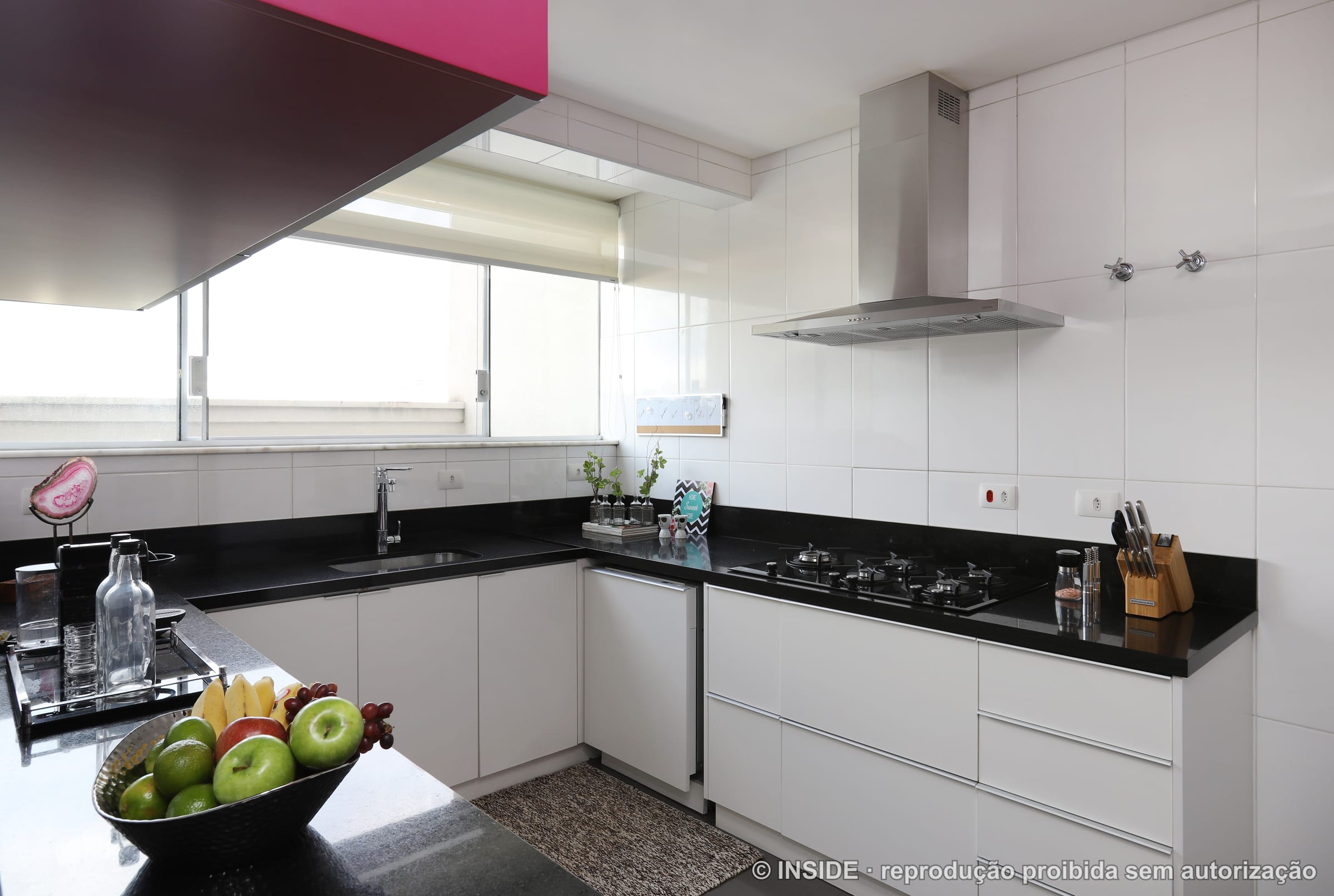 Cozinha com coifa suspensa, bancada de mármore e cooktop, iluminação natural, projeto INSIDE