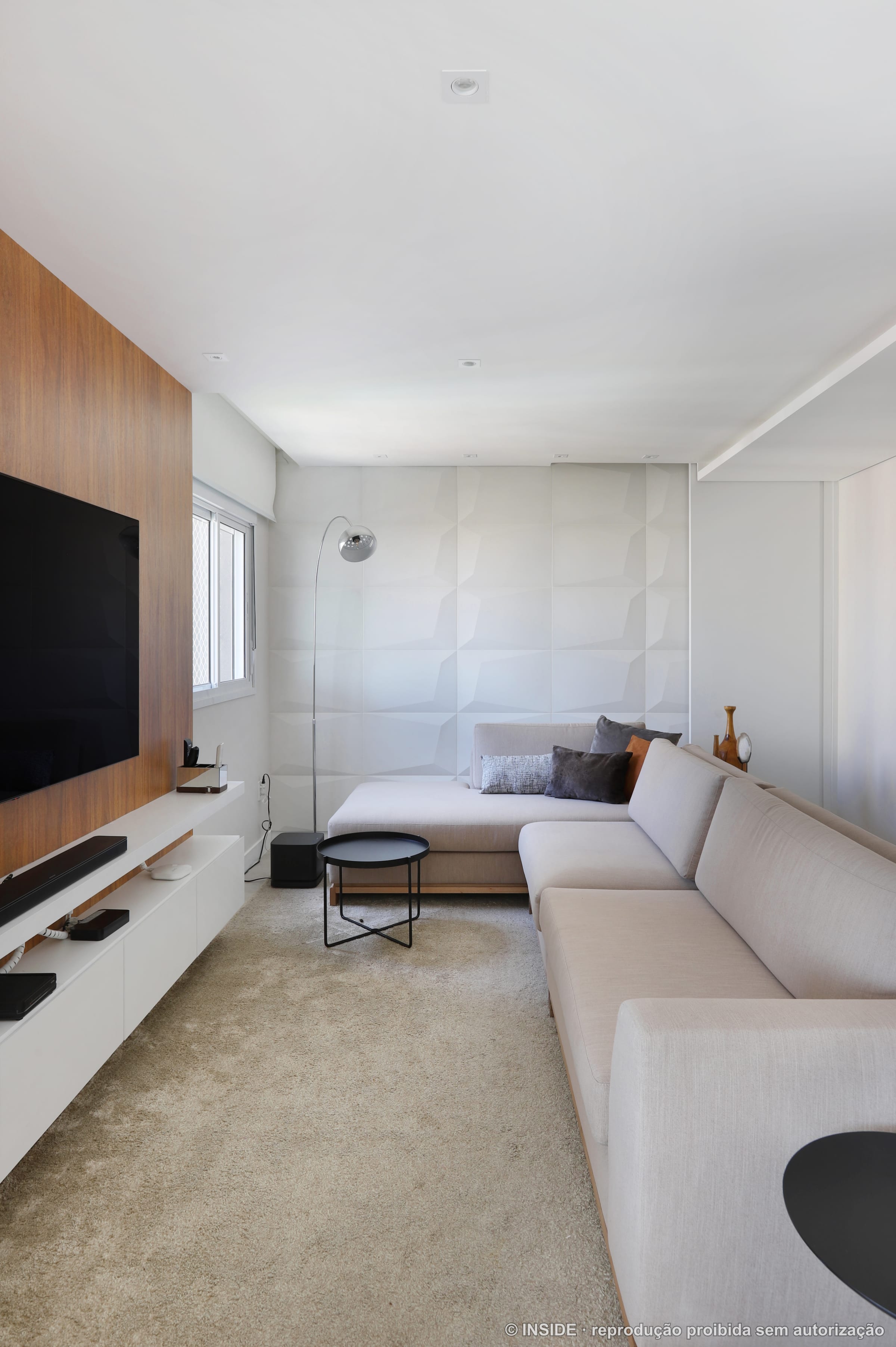 Sala de estar integrada com painel ripado de madeira, televisão e sofá em L claro, projeto INSIDE