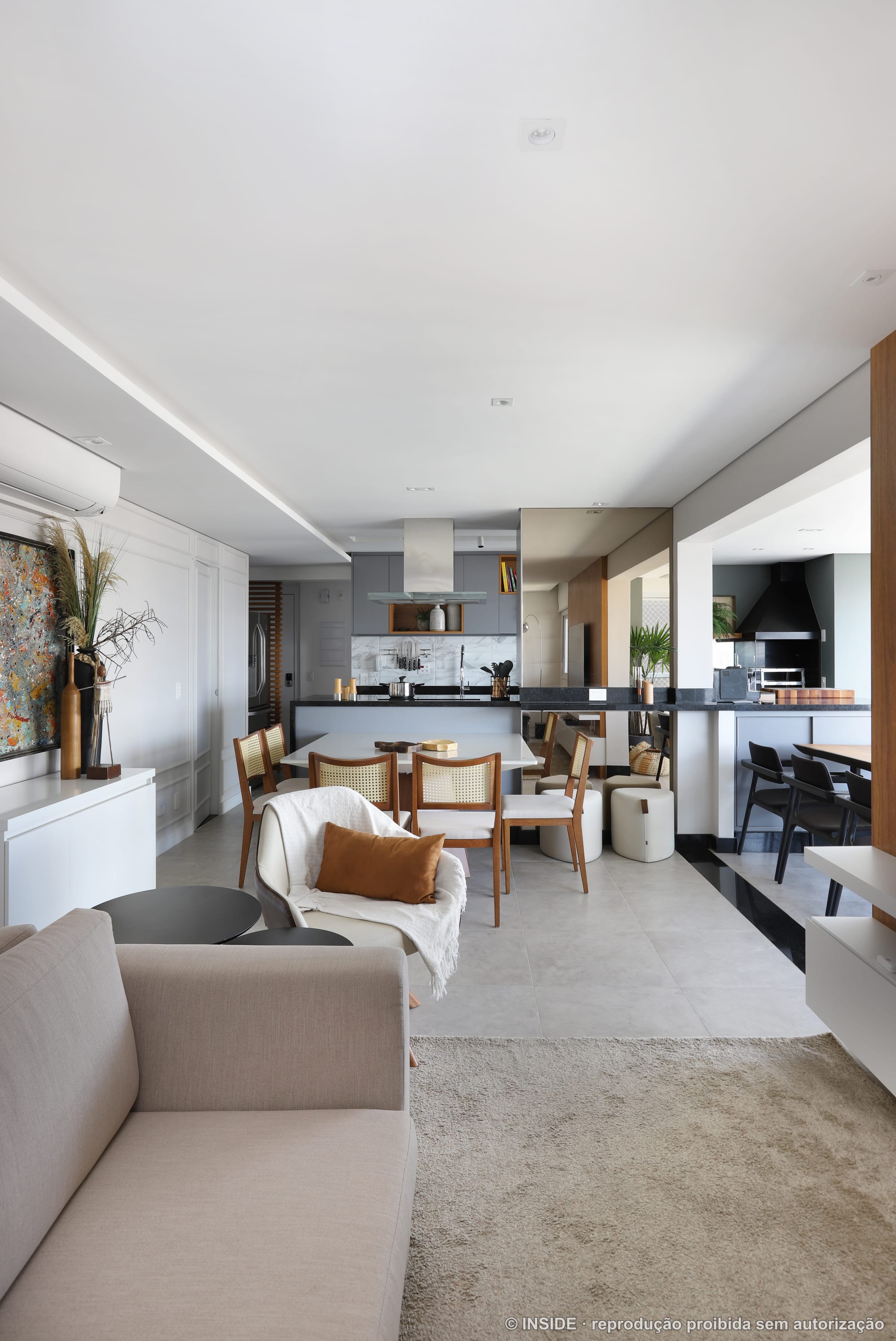 Sala e jantar integrados em tons claros, com poltronas e mesa ao fundo, projeto INSIDE