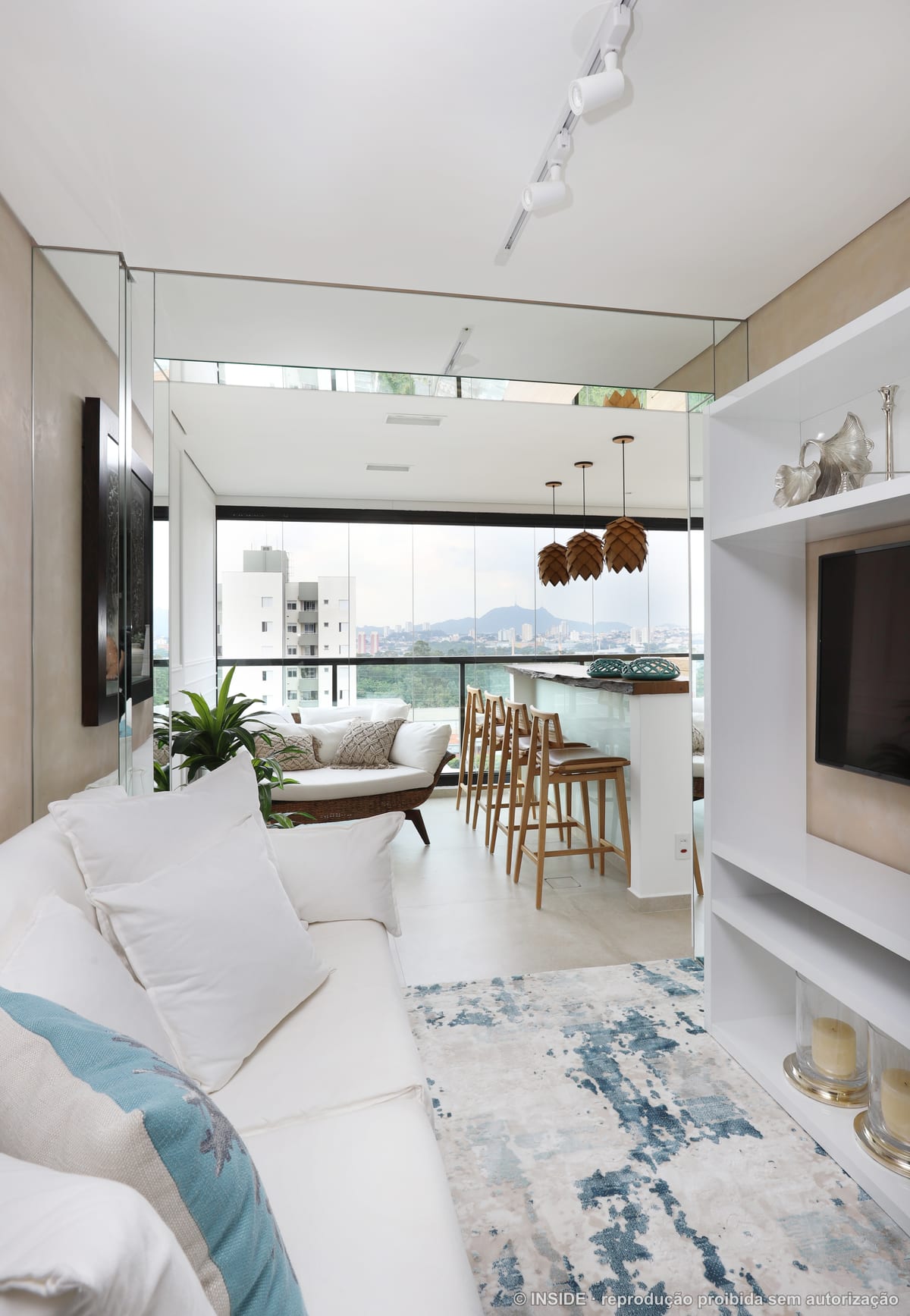 Living integrado com sofá branco, banquetas de madeira e piso-teto envidraçado com vista da cidade, projeto INSIDE