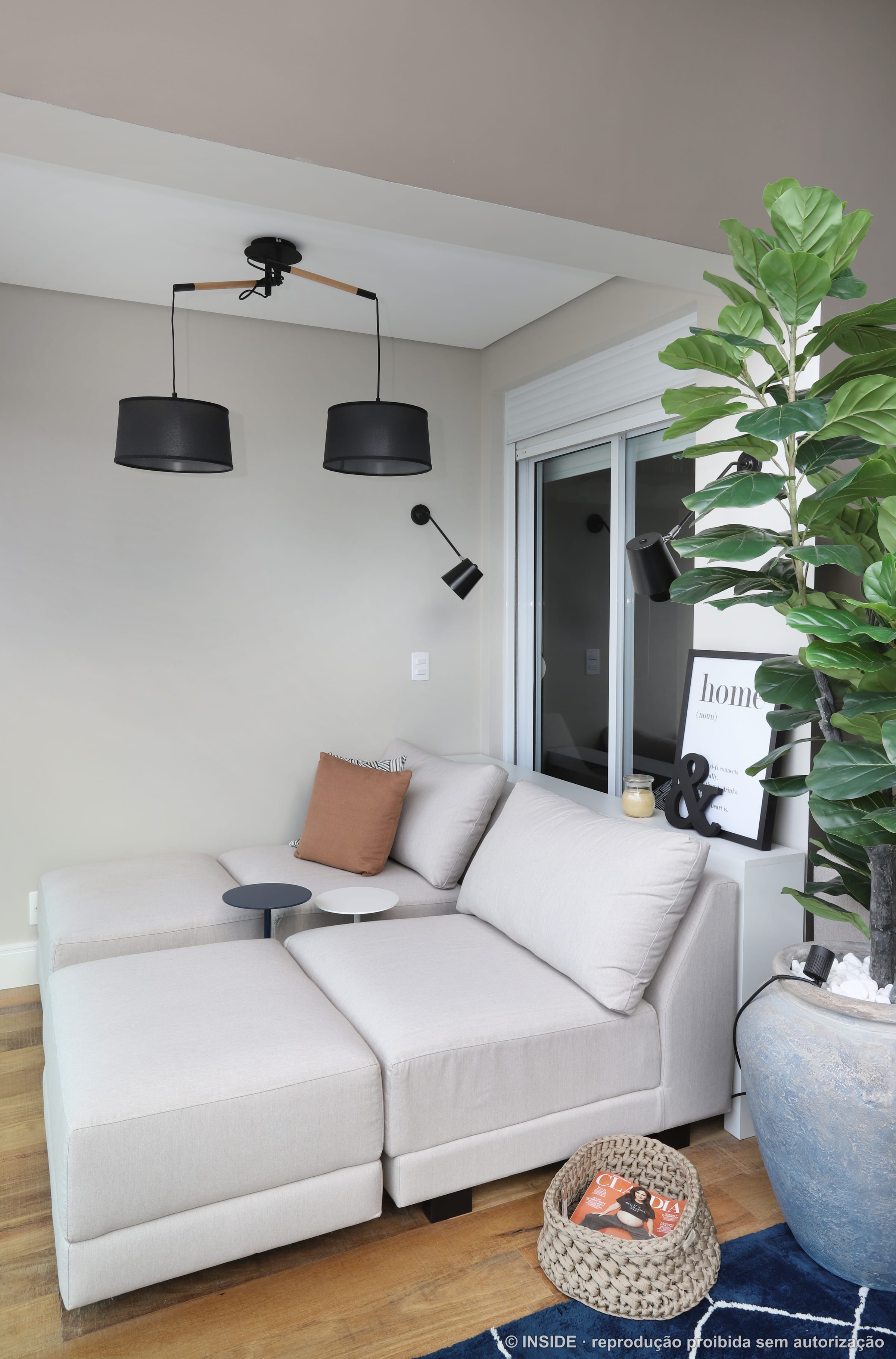 Estar de varanda com sofá branco, luminárias pendentes pretas, tapete azul e plantas em vaso, projeto INSIDE