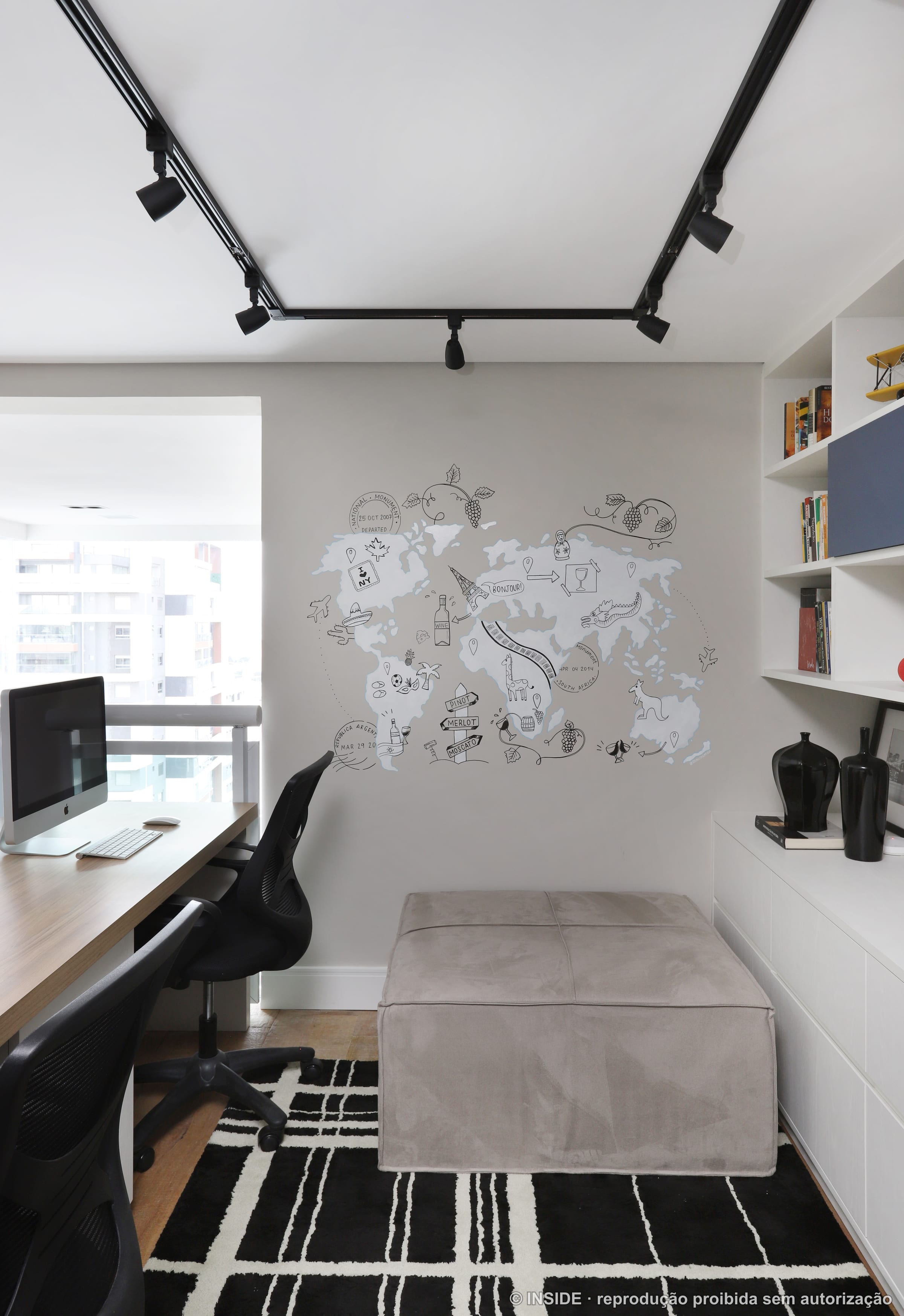Home office com bancada de trabalho, obra em relevo branco, trilho de spots e tapete listrado preto e branco, projeto INSIDE