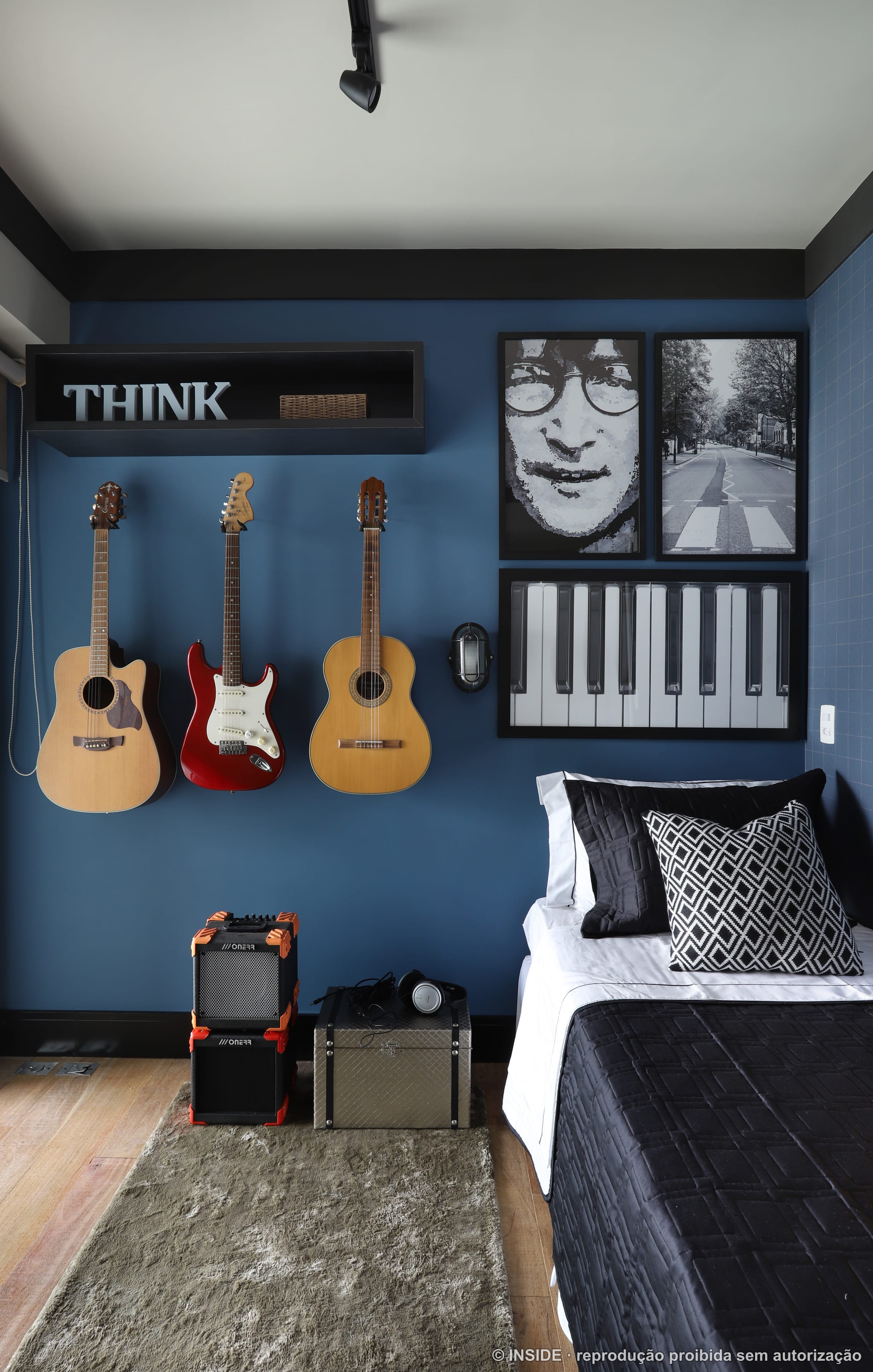 Quarto de menino com guitarras penduradas como arte, pôsteres em preto e branco sobre parede azul e cama com roupa de cama escura, projeto INSIDE