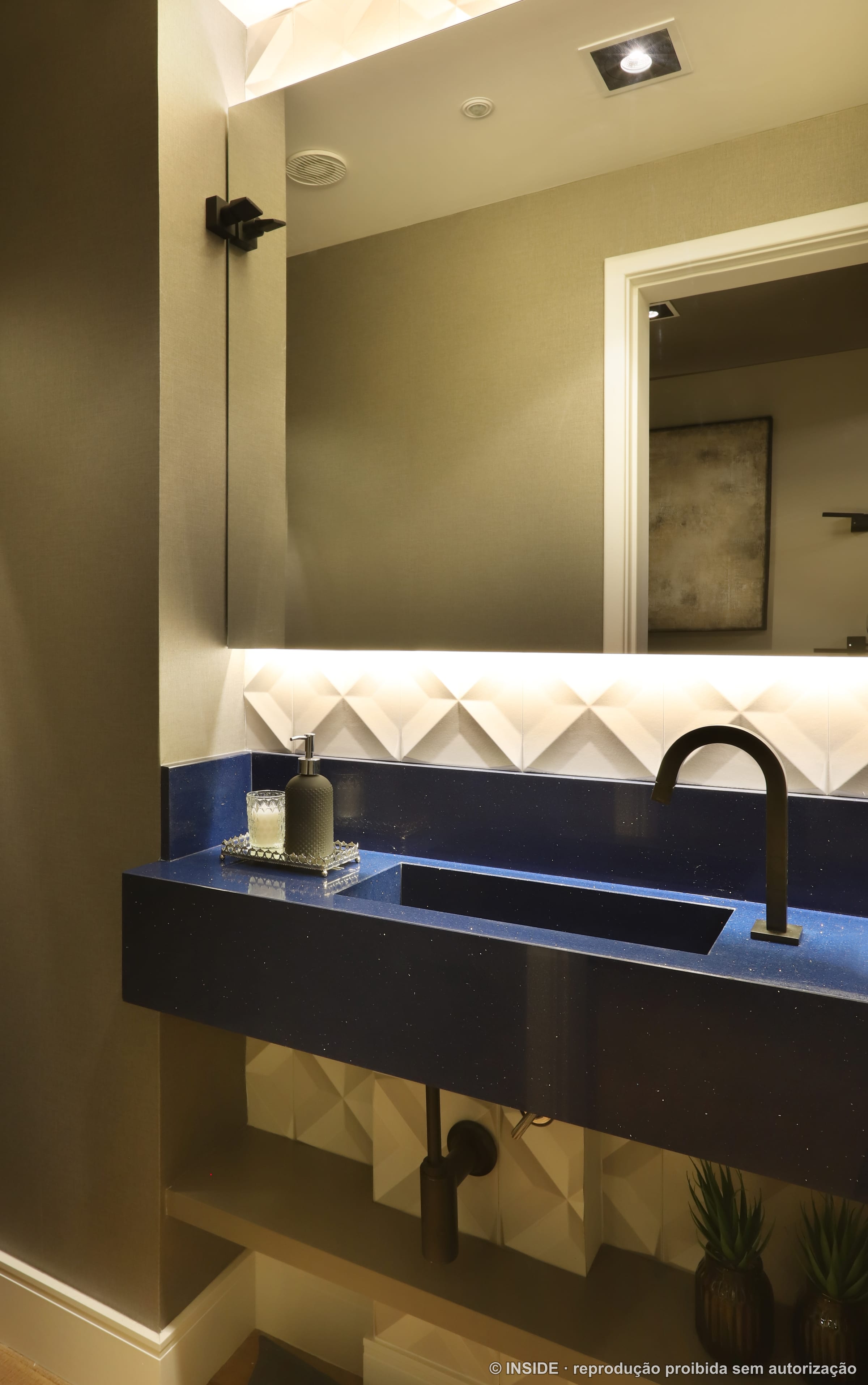 Lavabo com cuba escura esculpida, metais dourados, espelho iluminado e revestimento geométrico em tons de bege, projeto INSIDE