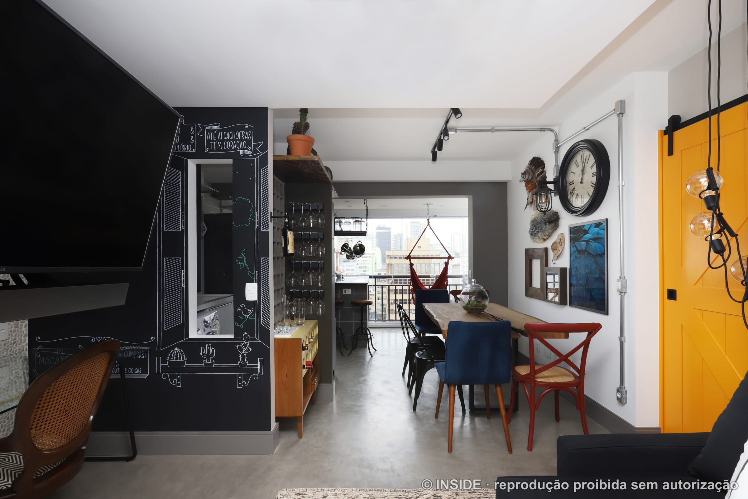 Corredor integrado ao estar com porta estilo celeiro amarela e sofá escuro, projeto INSIDE