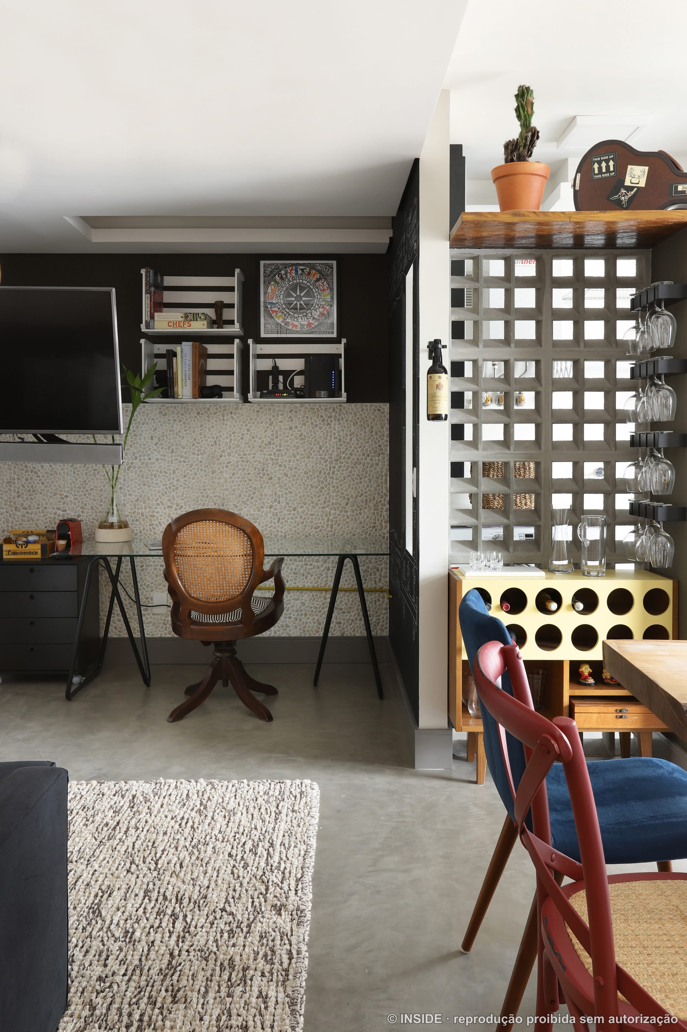 Canto de home office com escrivaninha, cadeira de vime vintage e prateleiras metálicas, projeto INSIDE