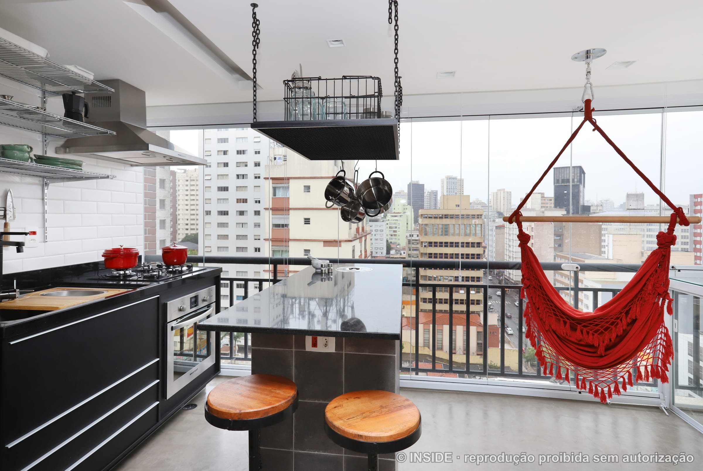 Cozinha industrial aberta para a varanda com rede vermelha e vista da cidade, panelas vermelhas, projeto INSIDE