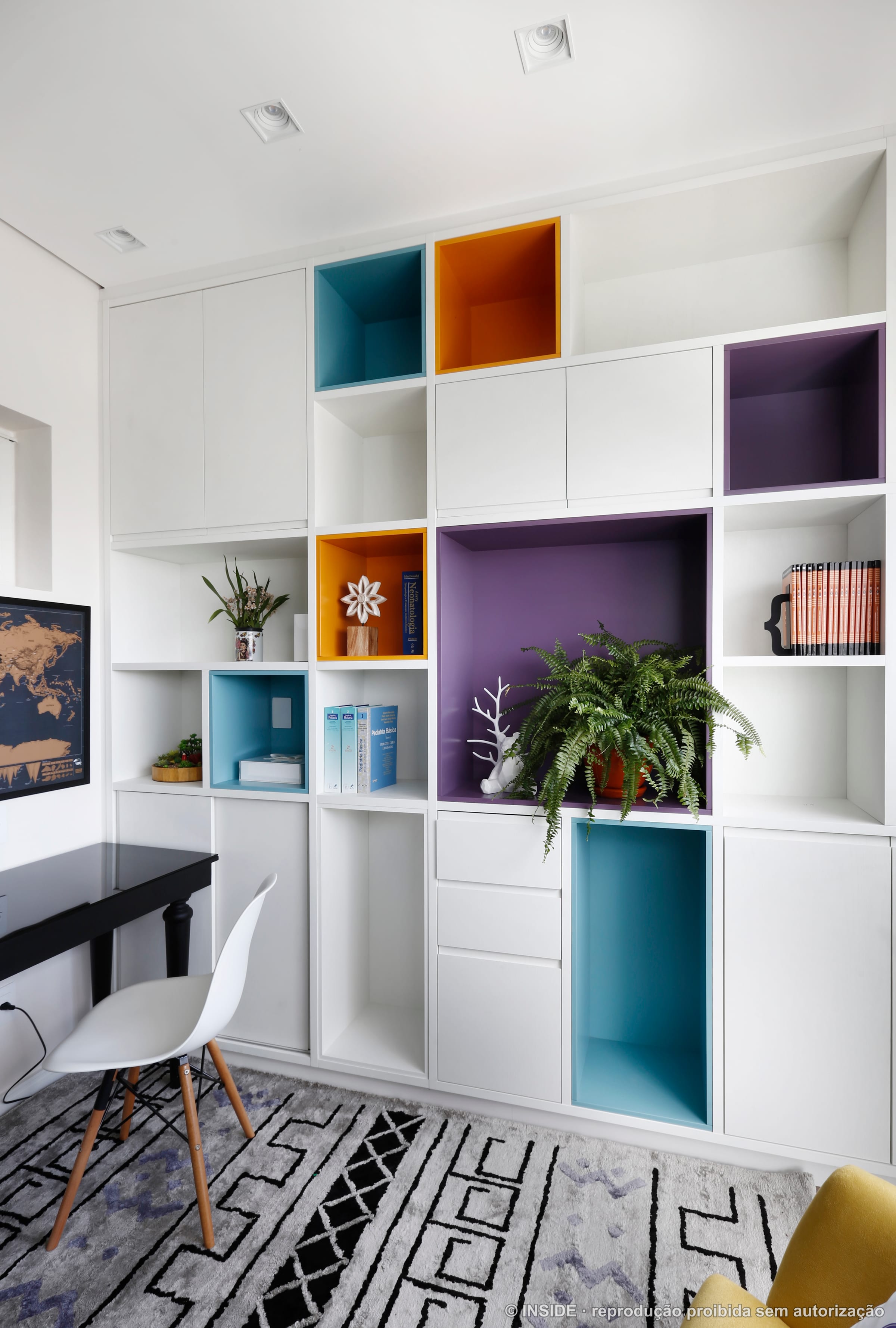 Estante com nichos coloridos, livros, plantas e poltrona amarela, projeto INSIDE