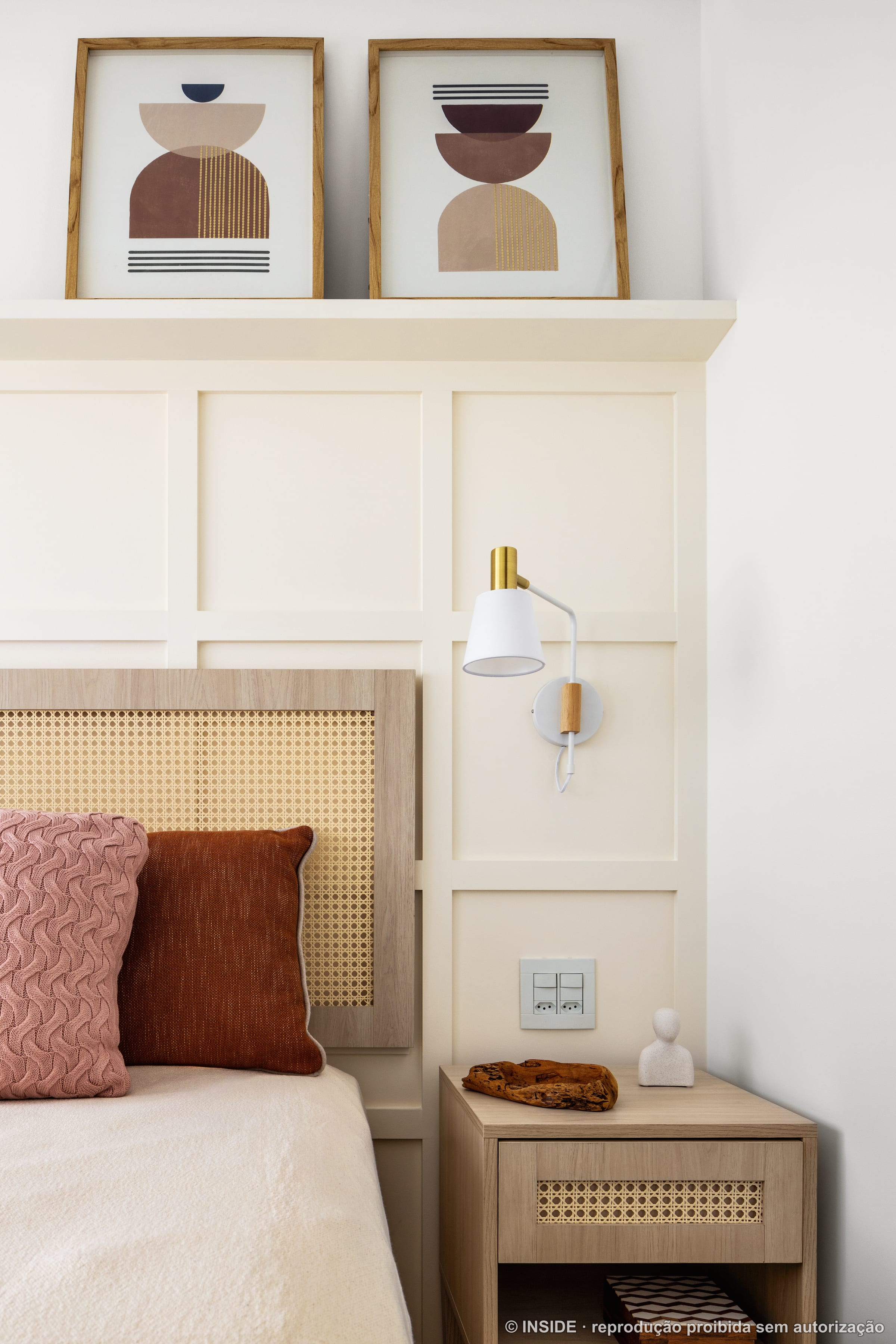 Quarto de casal com cabeceira em palha cana, abajur dourado, cama em tom creme e painel de lambri neutro, projeto INSIDE
