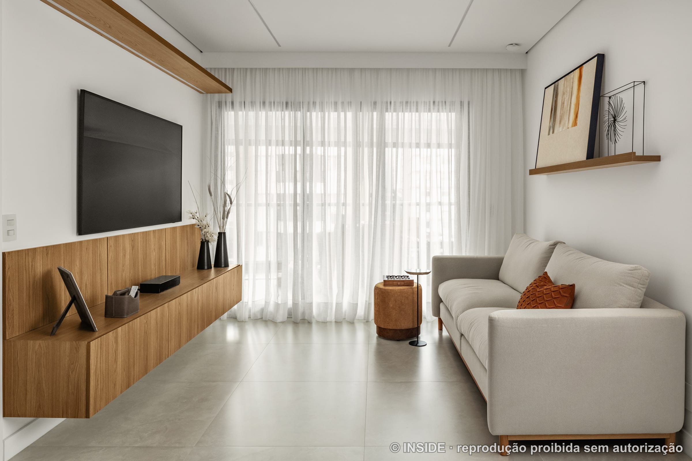 Sala de estar com sofá creme, painel de TV flutuante em madeira e cortinas brancas, piso natural, projeto INSIDE