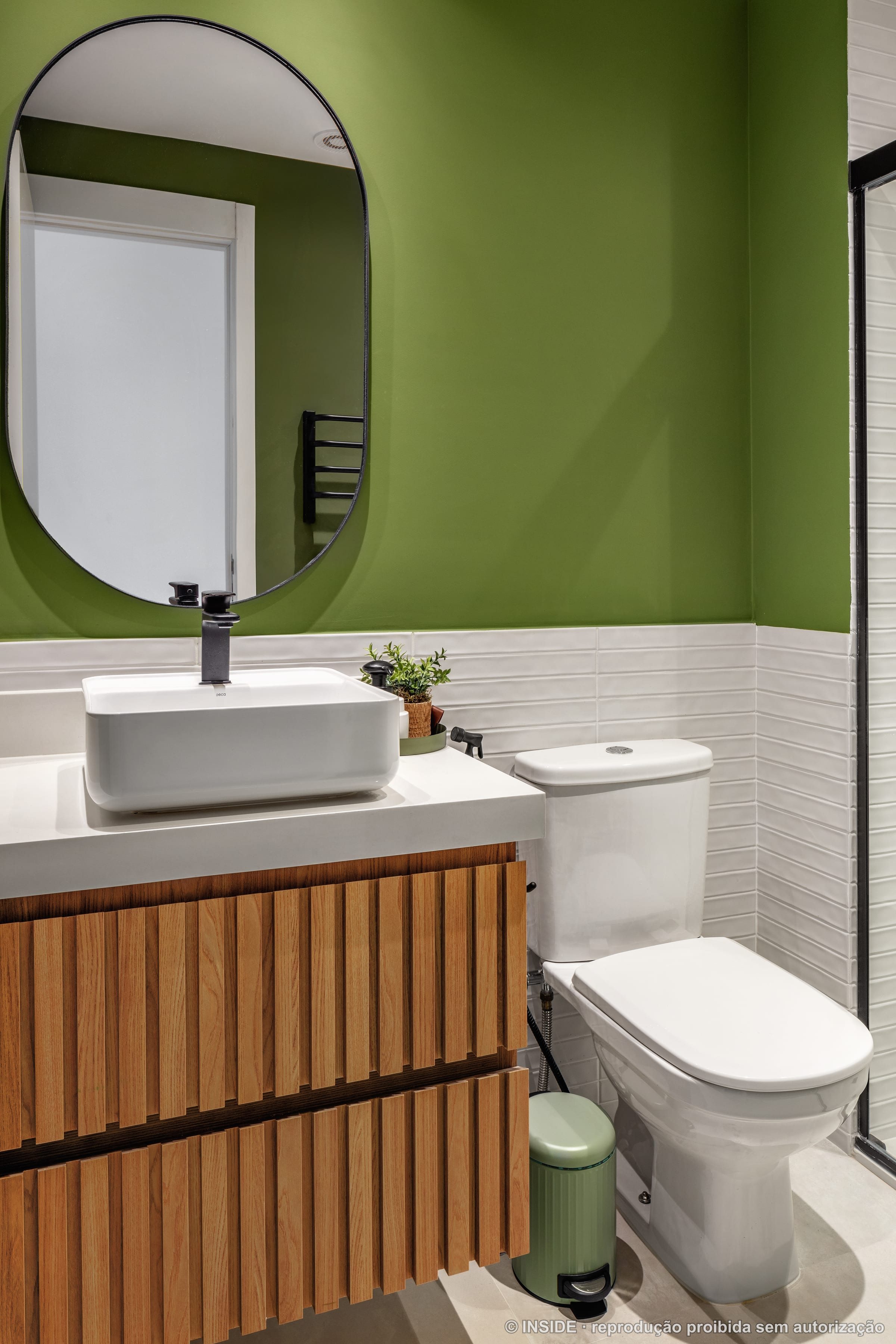 Lavabo com parede verde, espelho redondo, cuba branca de apoio e marcenaria ripada em madeira, projeto INSIDE