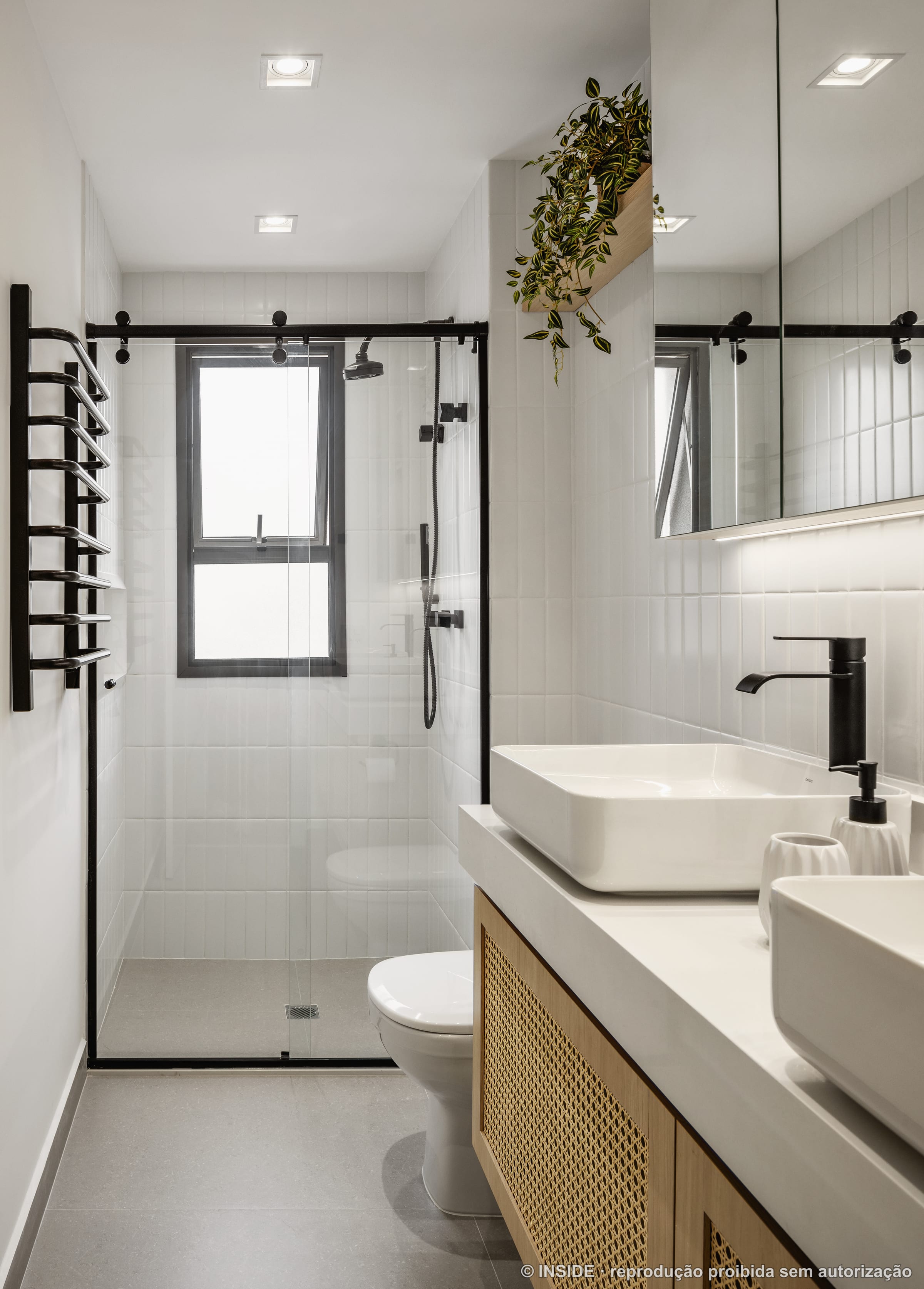 Banheiro com box de vidro, ducha e metais pretos, revestimento branco e plantas suspensas, projeto INSIDE